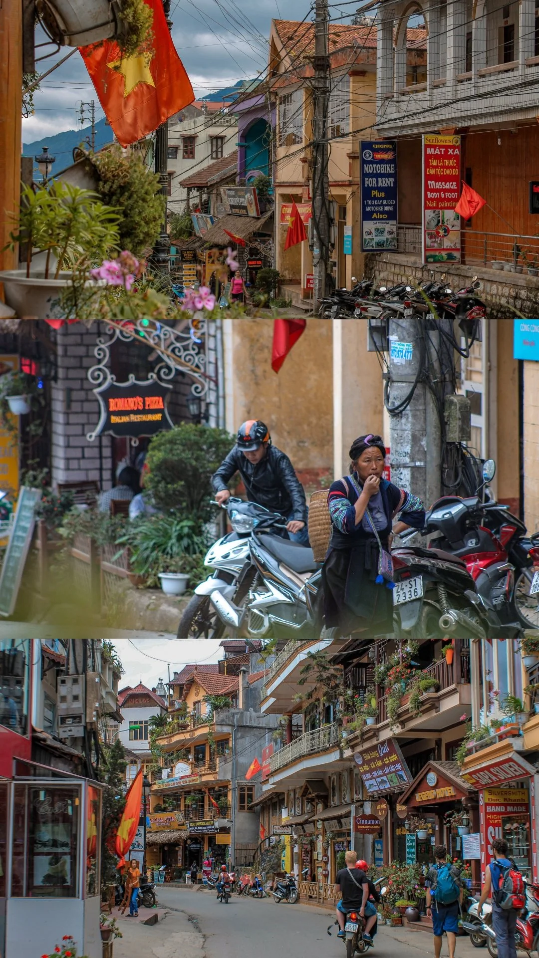 Street scene in a Vietnamese town with colorful buildings, motorcycles, pedestrians, and political flags.