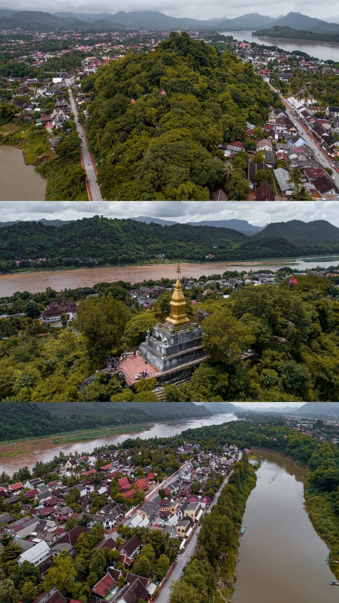 Aerial view of a lush green hill with a temple at the top, surrounding houses, a river curving through a valley, and mountains in the background under cloudy skies.