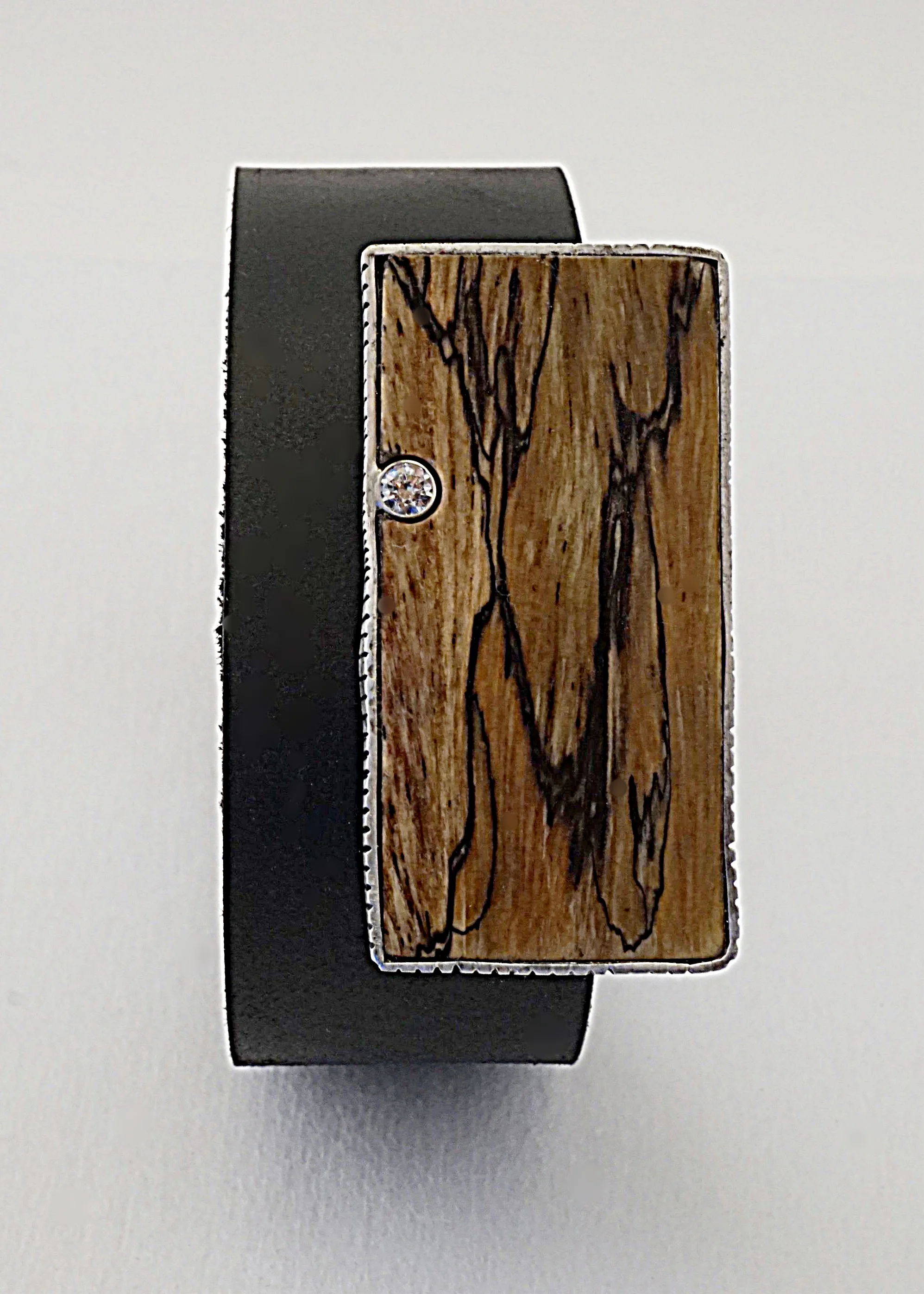 Splated tamarind wood with sterling silver bezel hand textured around wood and sterling silver bezel set with white sapphire on black leather