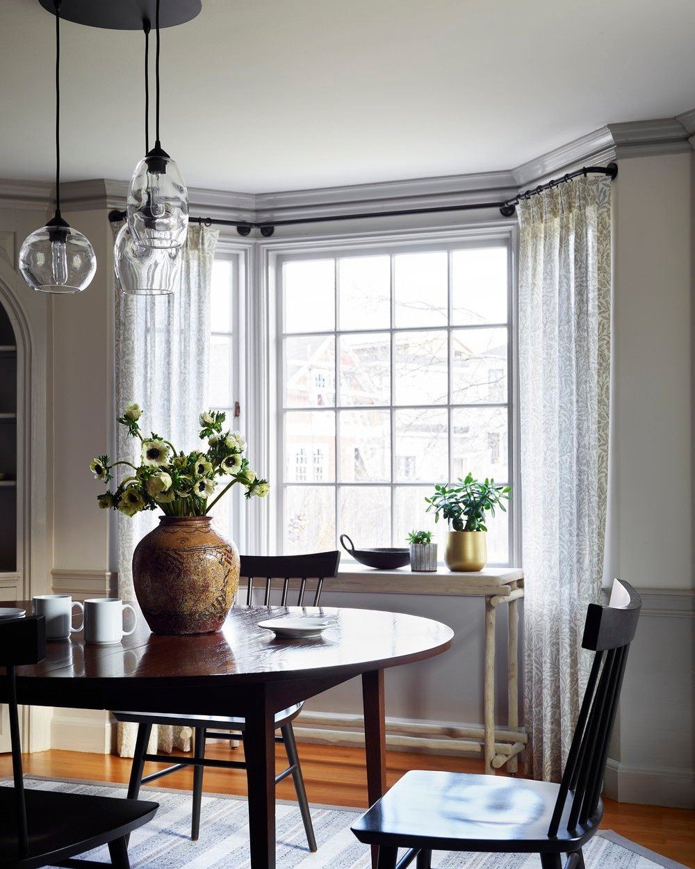 Doesn't the contrast of dove gray crown molding and wainscoting against rich dark woods feel so chic? I opted for sheer window treatments to add a soft touch. For a unique blend of styles, I paired fresh flowers and vintage-inspired accents with mode