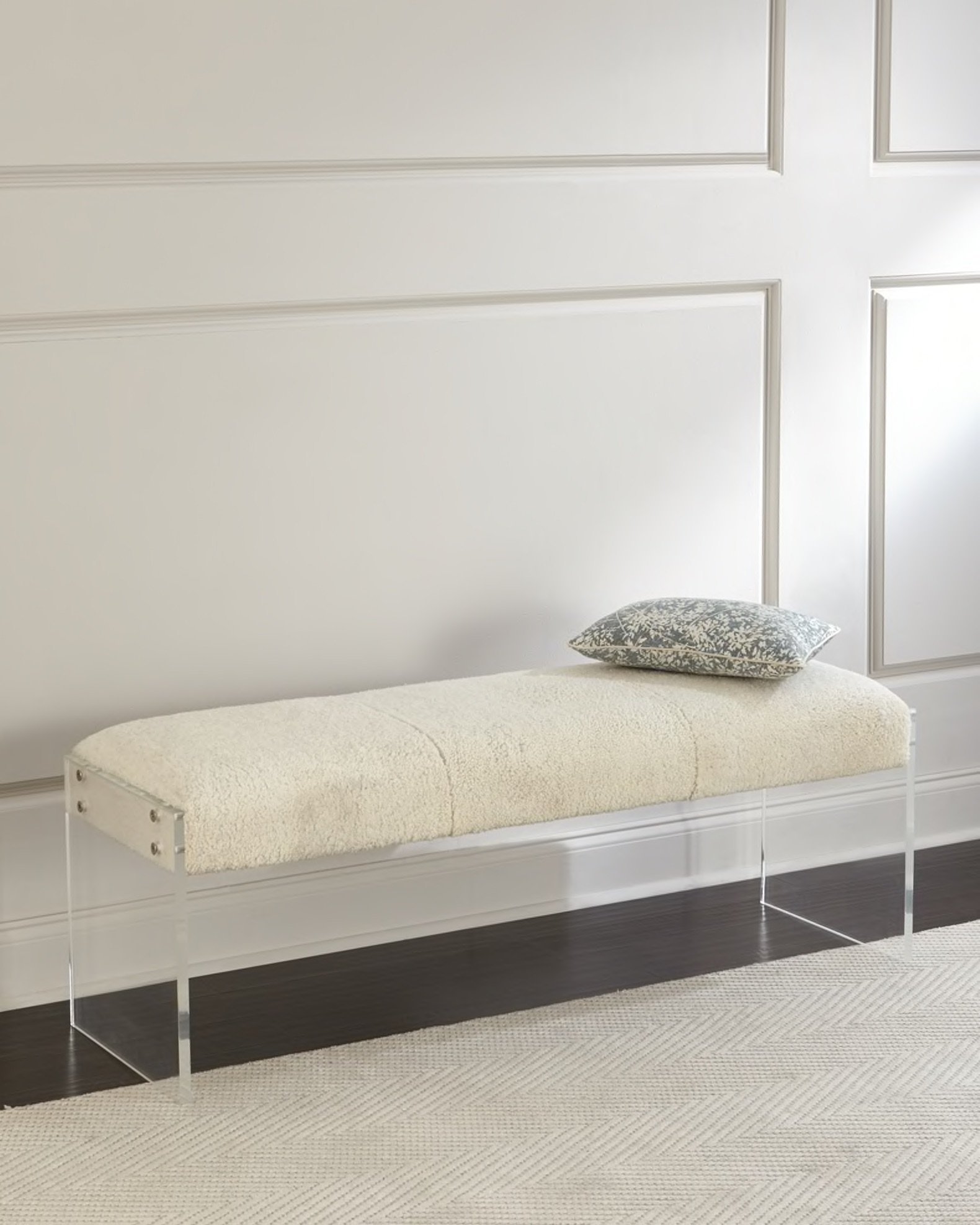 A cream shearling seat atop the sleek acrylic Aiden bench creates a decadent combination that not only offers comfort but also adds a touch of contemporary style to any space. I'm in love with the way the plush texture of the shearling contrasts with