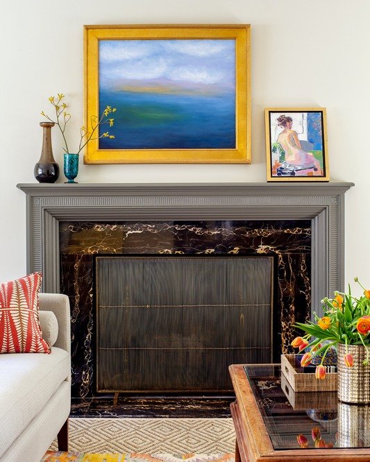 Do you love color and pattern mixing as much as I do? The exquisite original fireplace is undoubtedly the focal point, so I oriented the furnishings to lead the eye to the mantle, which is painted a striking shade of gray to highlight the fluted deta