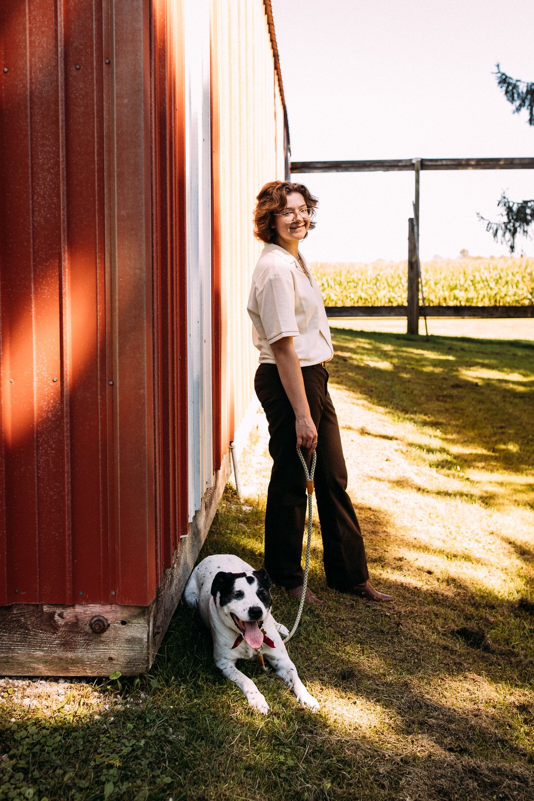 Photographer Brooke Kittell and her dog Snoopy stand in front of a red shed