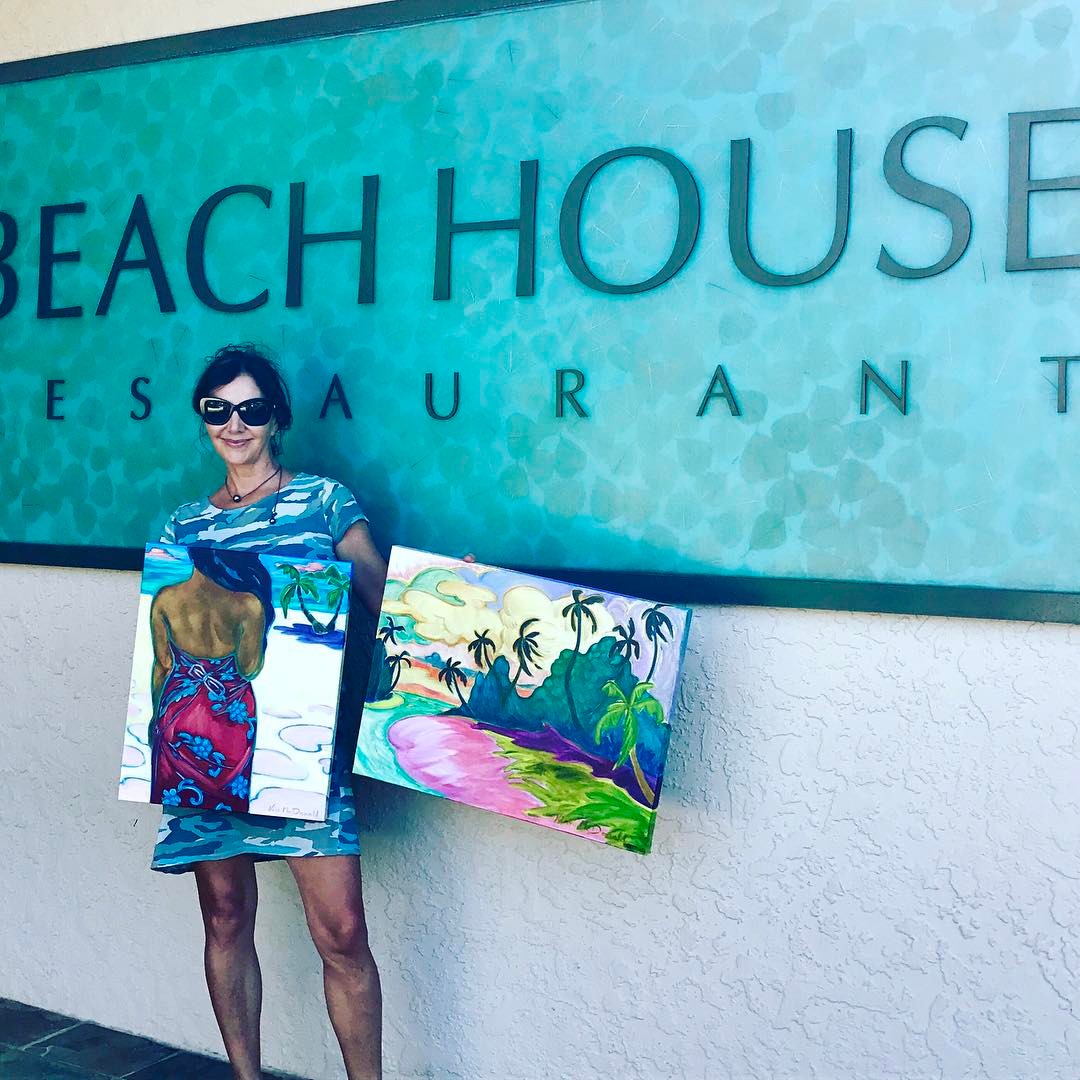 Kim McDonald holding two of her pieces in front of Beach House restaurant 