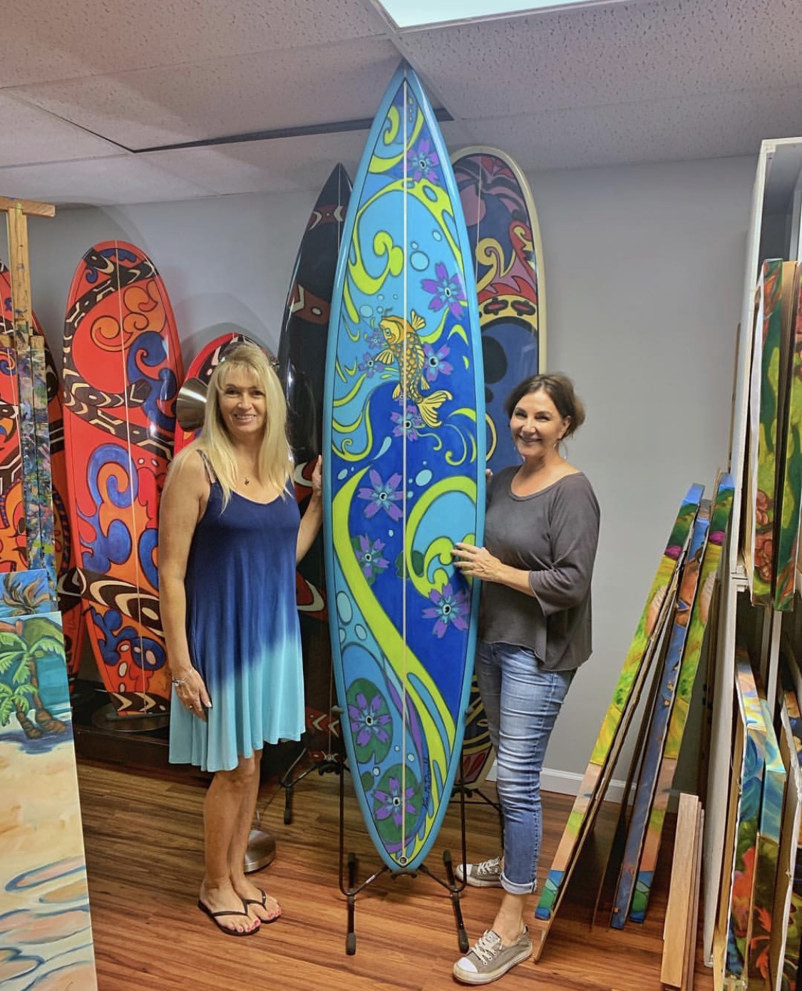 Woman posing with Kim McDonald and a Surf Board she painted