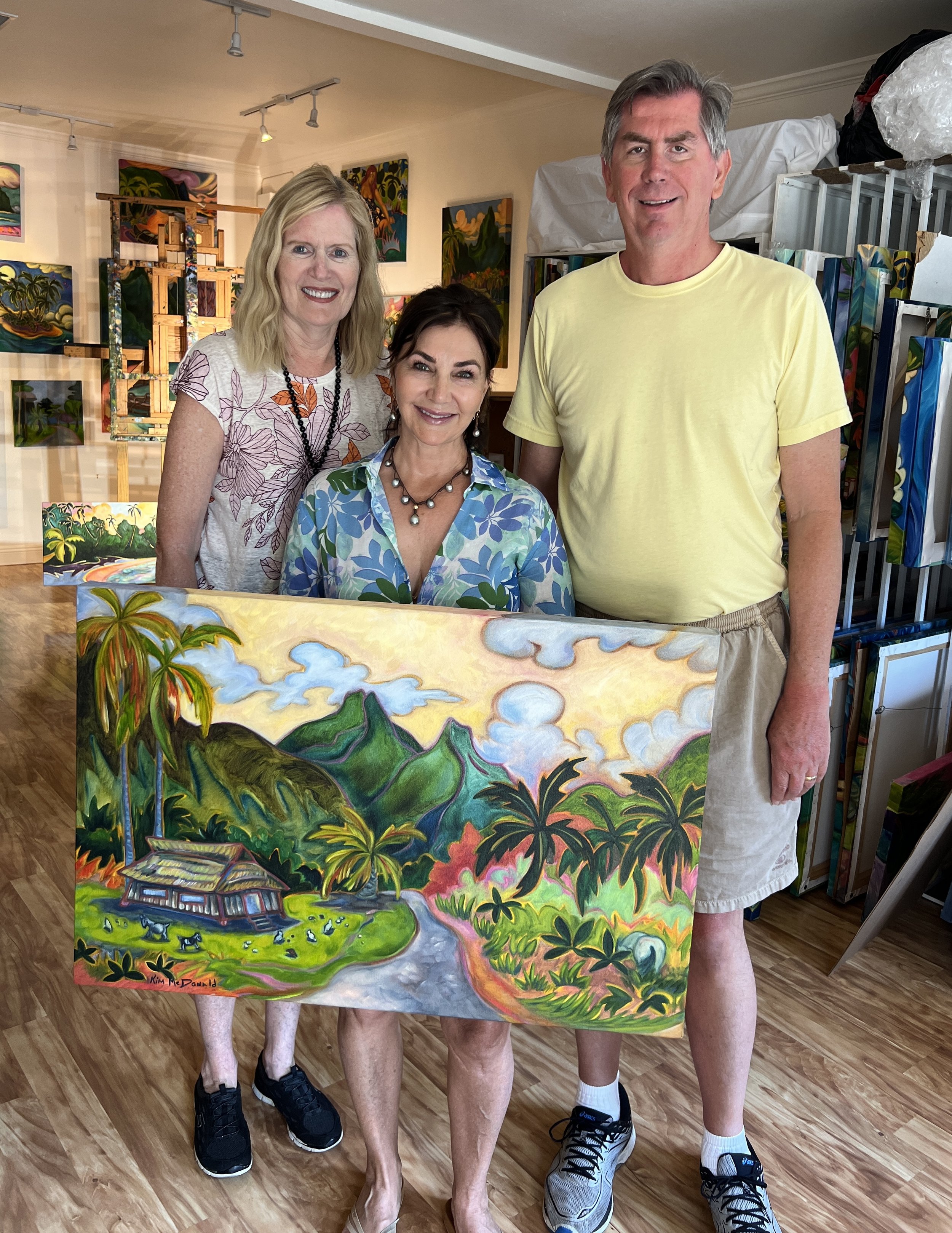 Couple posing with Kim McDonald and a piece of her art