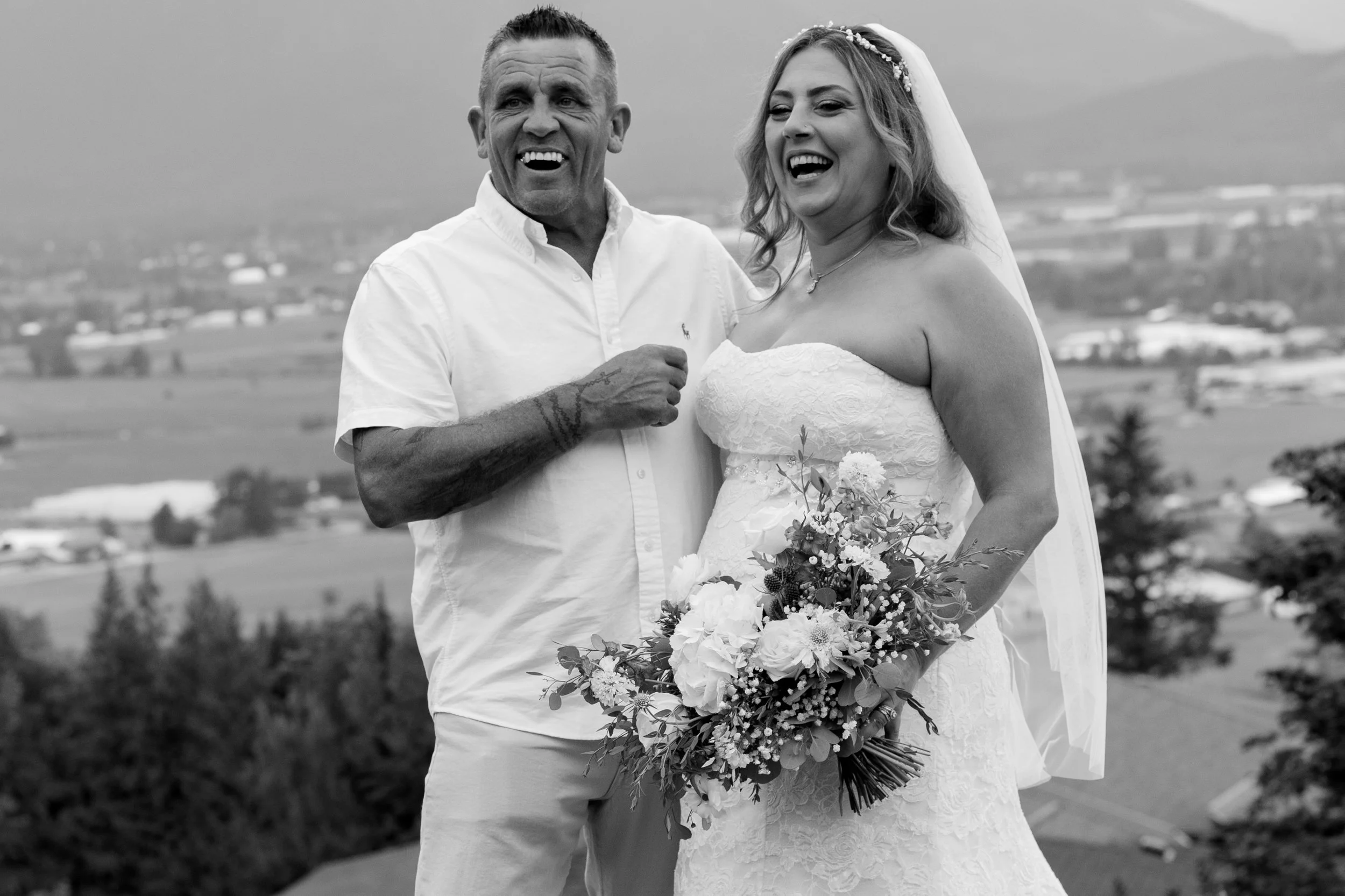 Black and white photo of a man and woman on a wedding day with a scenic background.