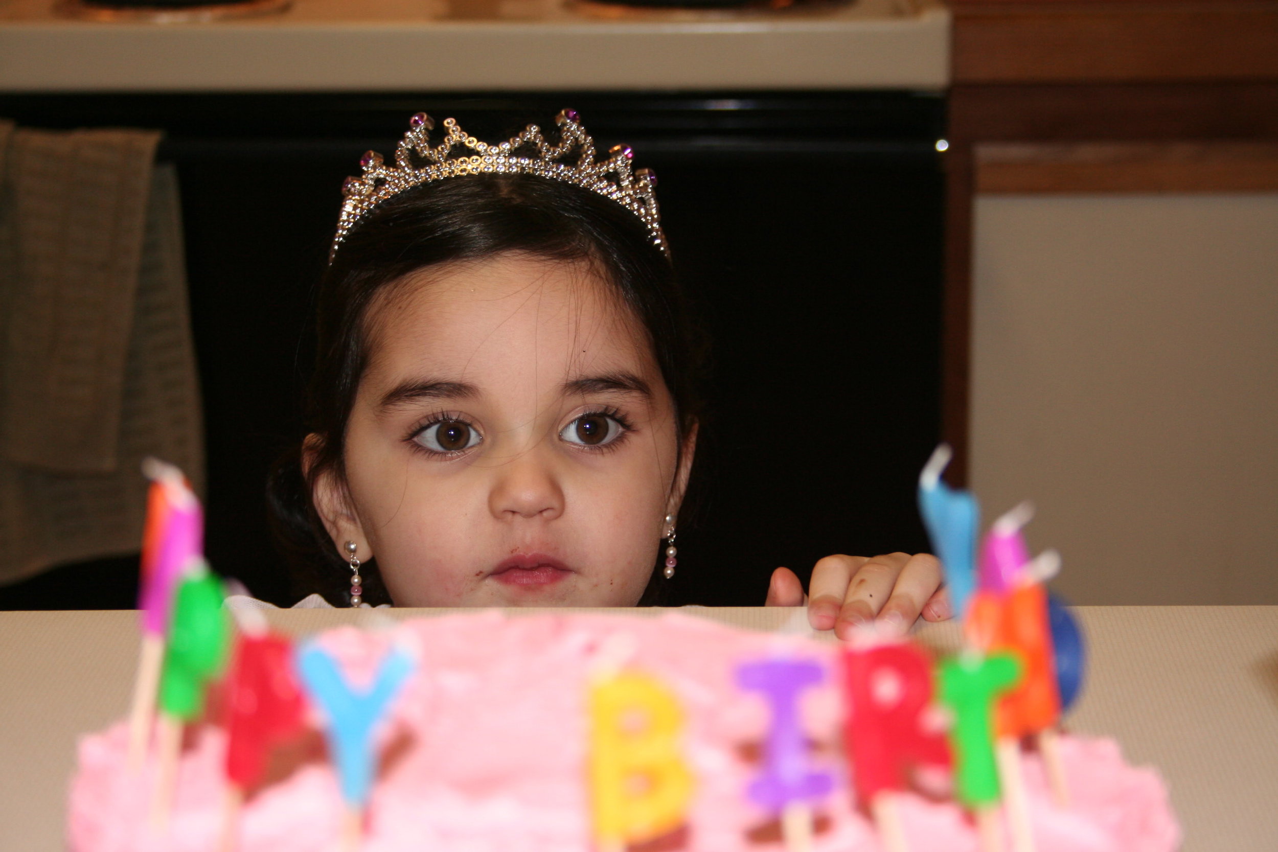 Capturing the awe in a child's face as she peeks at her birthday cake.