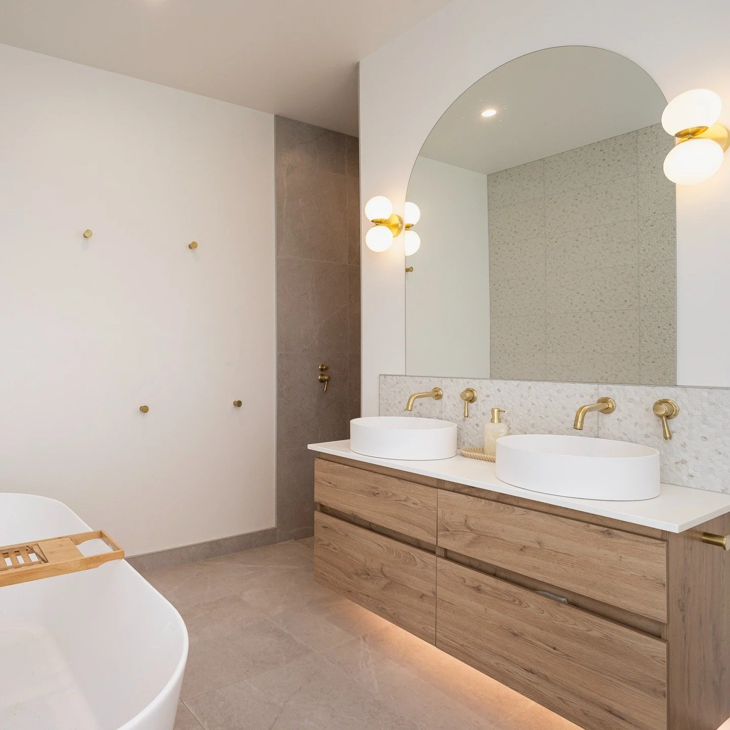 A serene ensuite bathroom in our recently completed Lincoln Farmhouse. Oak cabinetry, brushed brass fixtures/fittings and a muted palette bring a real calmness. The perfect getaway for Mum and Dad! With central his/hers basins (shower and toilet are 