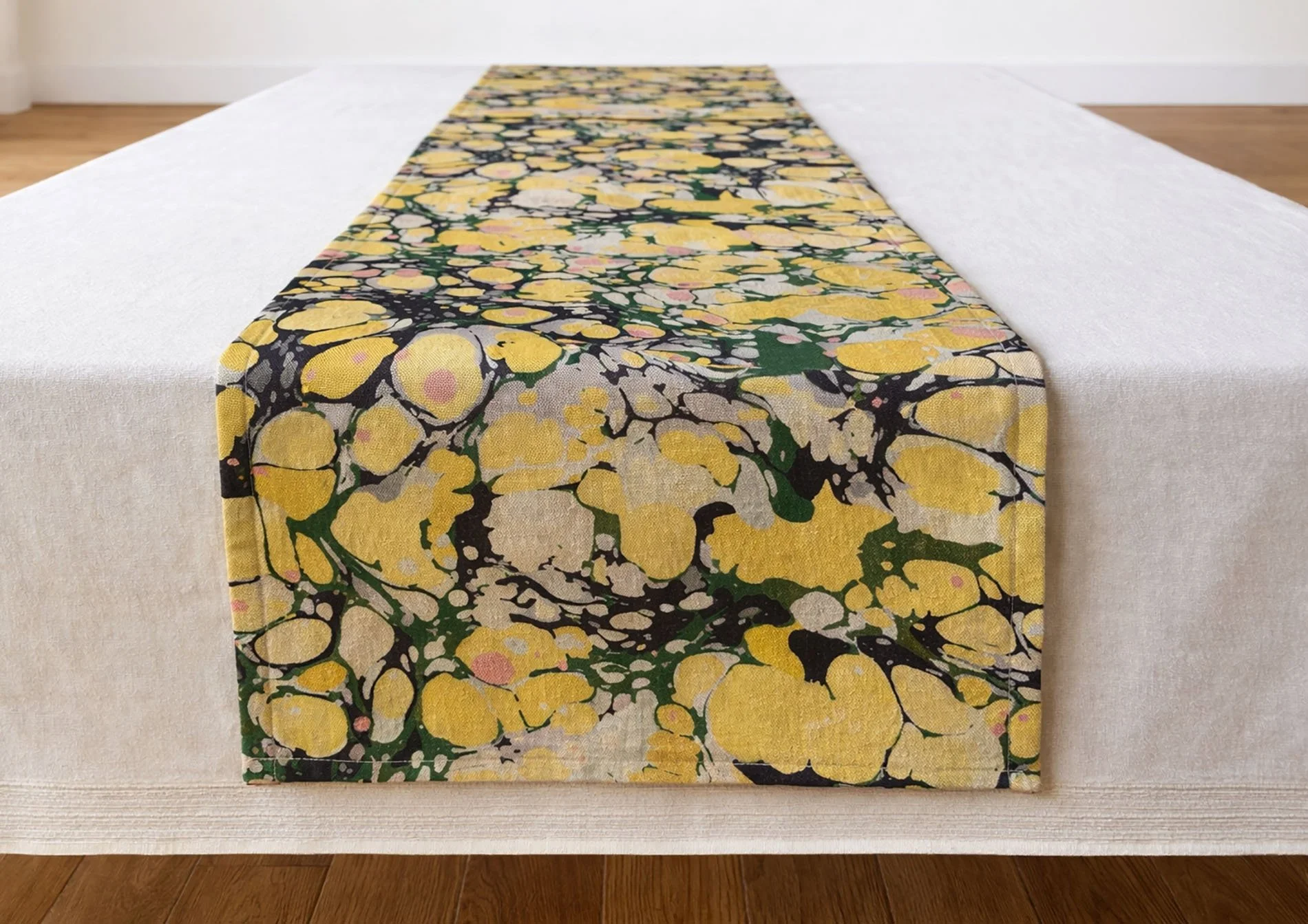 Long marbled table runner La Forestina placed across linen tablecloth in natural tones