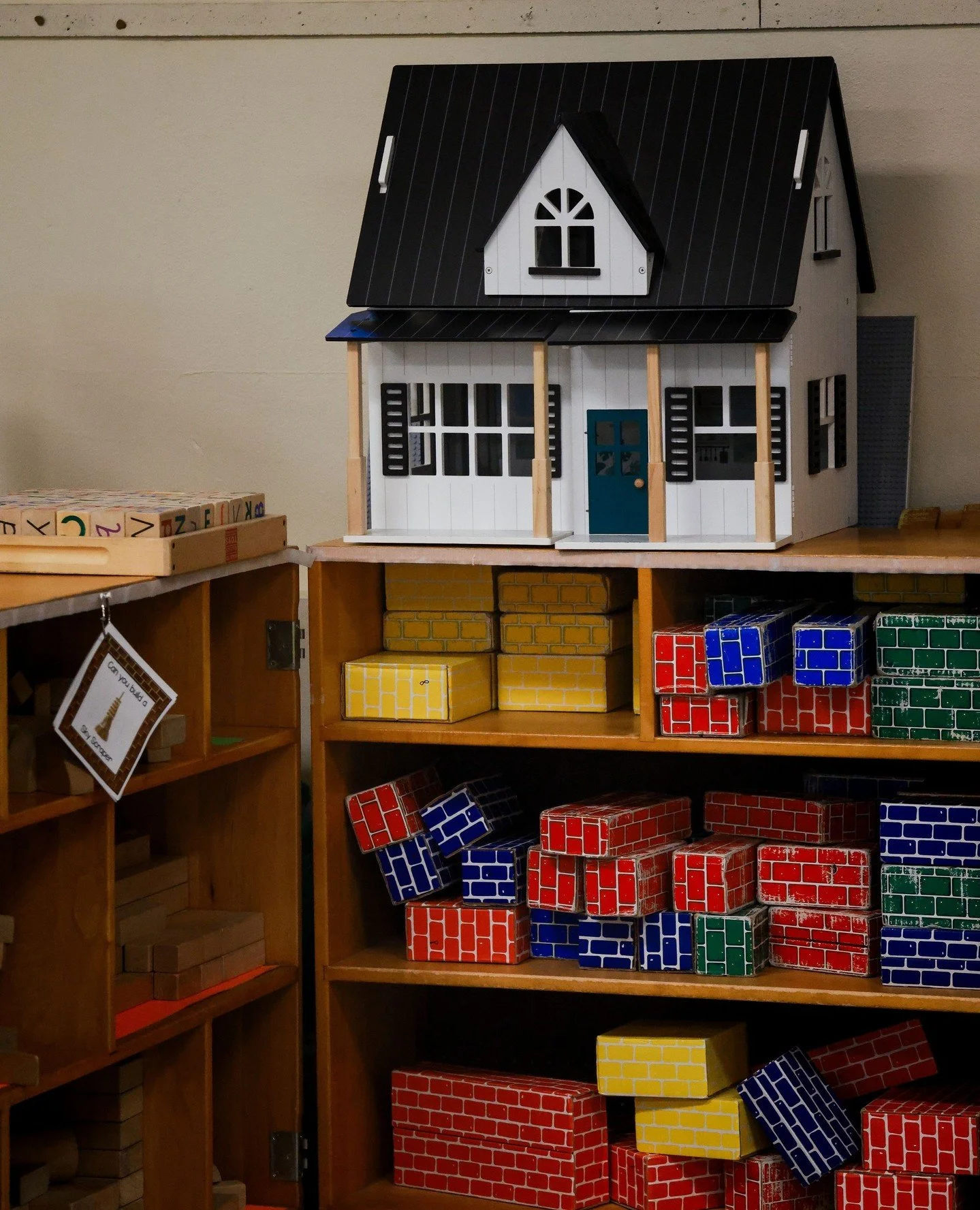 Our play-based responsive classroom uses open-end toys like blocks and compact dollhouses to support child-led learning, social-emotional growth, and cooperation.