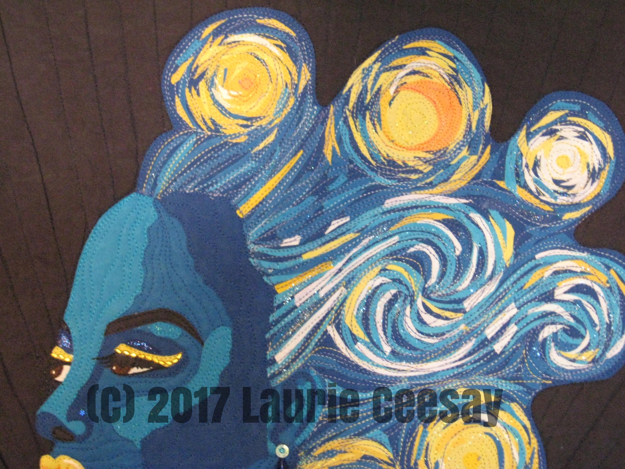 This photo shows more of the face. I used tiny gold rhinestones from The Dollar Tree in the nail art department for eyeliner. Shimmery nail polish is on the lips and in the hair. I used some brown Derwent Inktense pencils to define the mouth. I named my entry "Vincentia" after Van Gogh's first name. Last year there was a huge amount of entries and only a third of them made the cut. I can only hope this quilt is as fortunate.