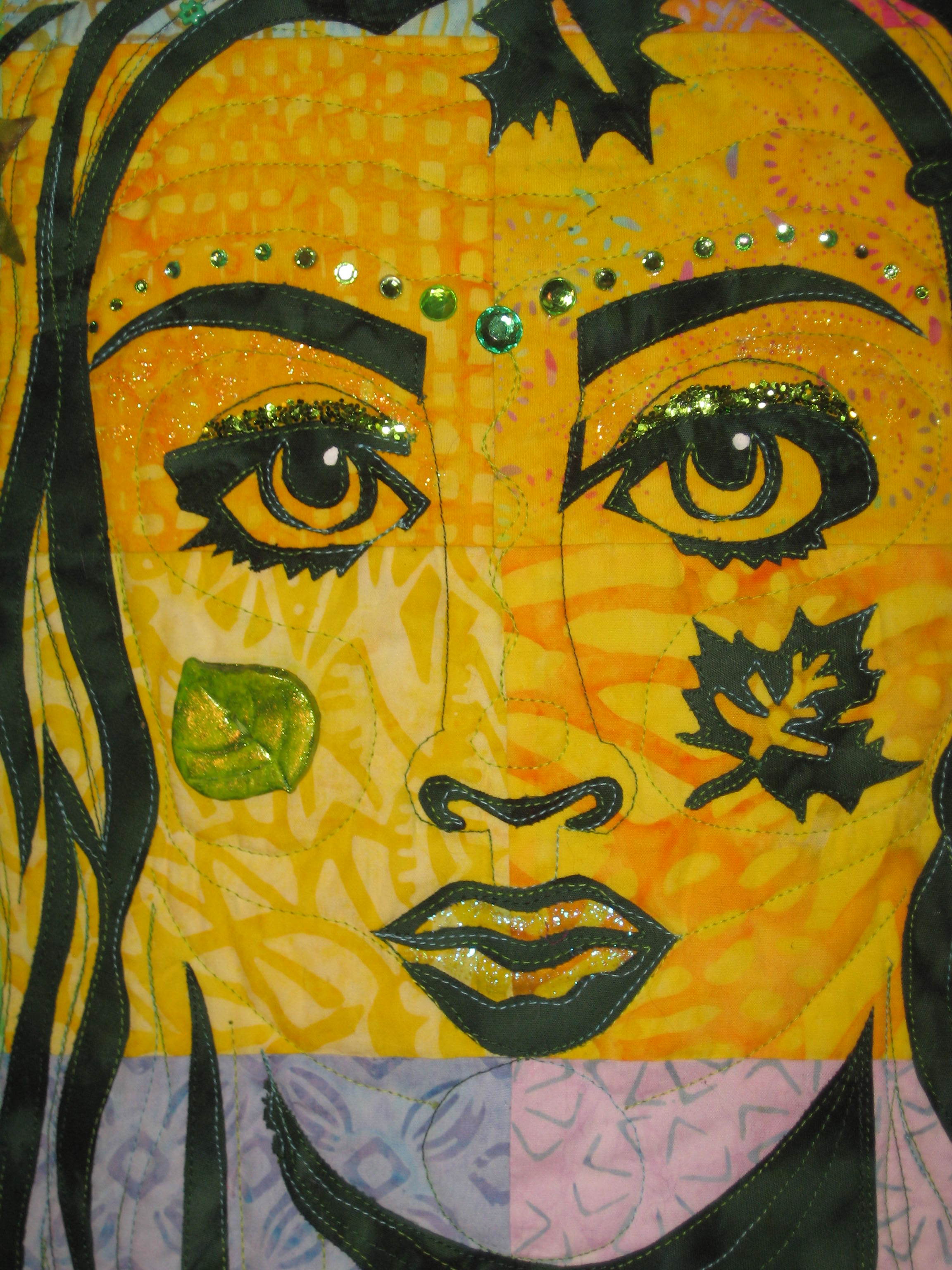 This is the close-up photo of the face with the quilting and the embellishing complete. I pulled from my embellishment stash any leaf or flower, large or small, in a variety of green colors. I added green rhinestones and loose glitter, glitter nail polish and a large glittery bead for the center of the necklace. Lots of sizes of green rhinestones above the eyebrows. The polymer button on the left cheek is painted with green nail polish to shine it up some! I took apart bracelets to use the green beads in this project-anything to have lots of green embellishments!Also silk flower scatter from The Dollar Tree stitched to the quilt in the crown area in between the applique leaves.