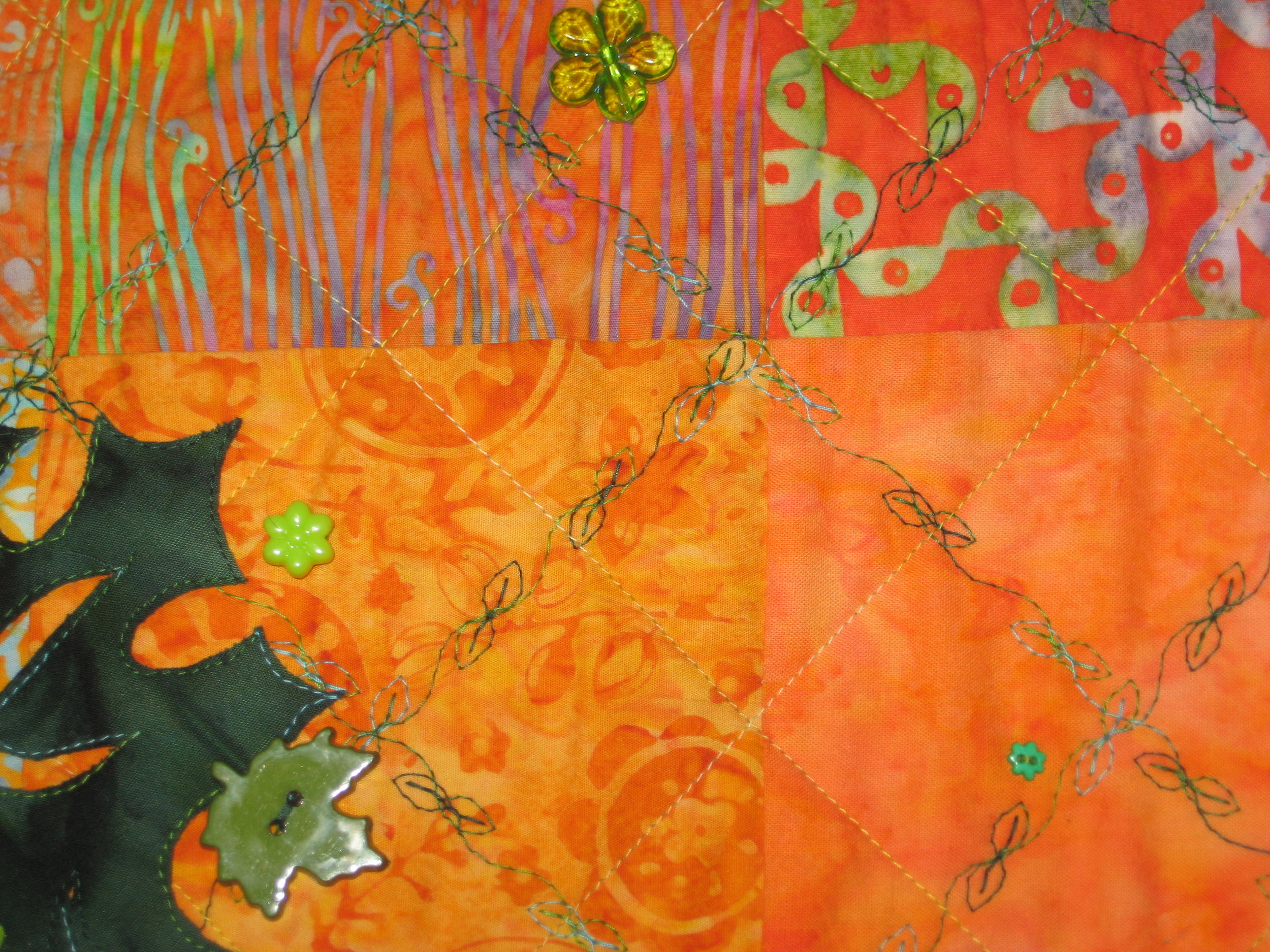 This photo shows the quilting of the background using a variegated thread and a fun leaf decorative stitch on my sewing machine. I did all the background quilting before I added the leaves on the crown area. I fused and stitched those on after the quilting was finished.