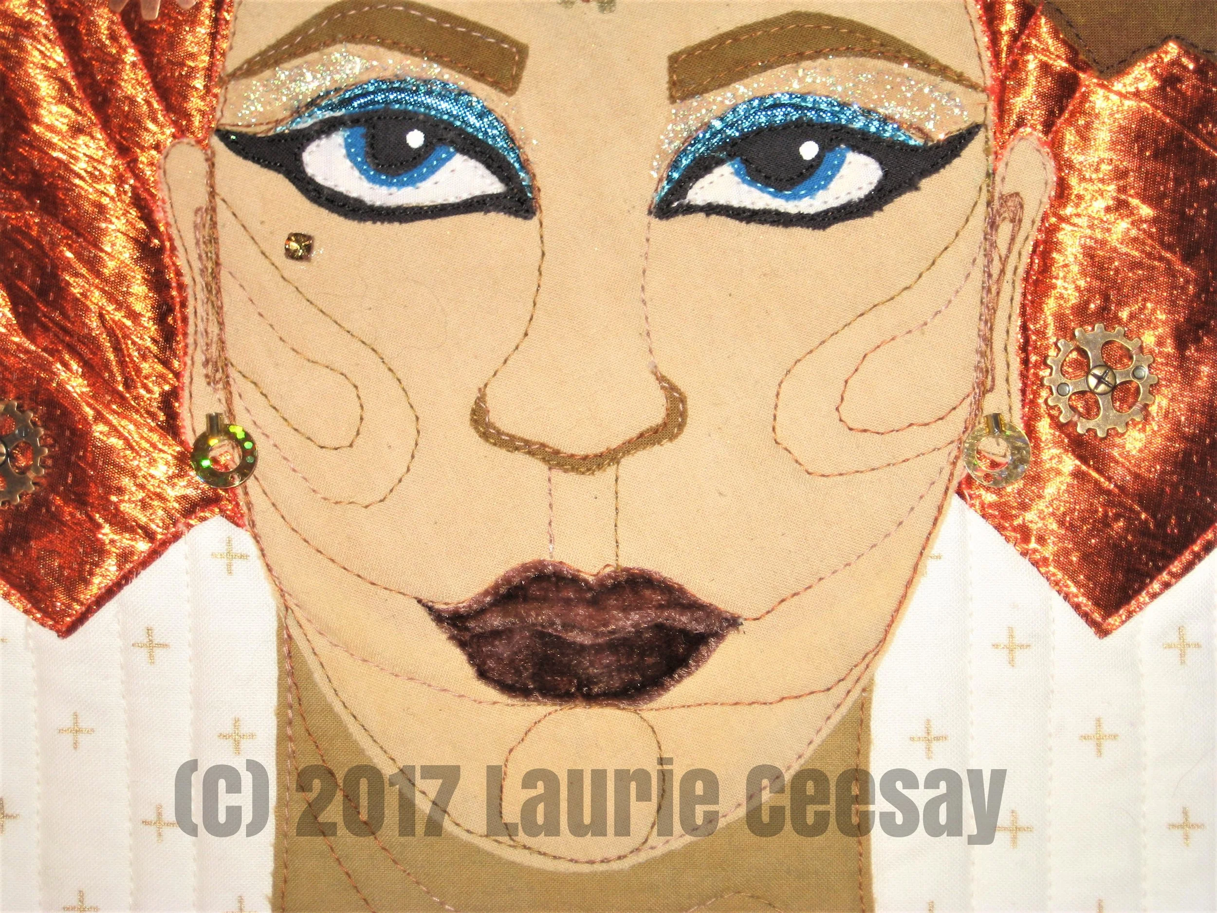 This is the close up of the face. Again I used Cherrywood Hand Dyed Fabrics for the skin tones because I love them! I used the same turquoise lame on the eye lids as in the gears. I found a hand dyed brown velvet for the lips. When one sews garments with velvet the nap of the velvet must go in the same direction or it looks like different shades. I purposely placed the upper and lower lip applique pieces in the opposite direction to look like two different fabrics. I used two glitter nail polishes in the eye area.