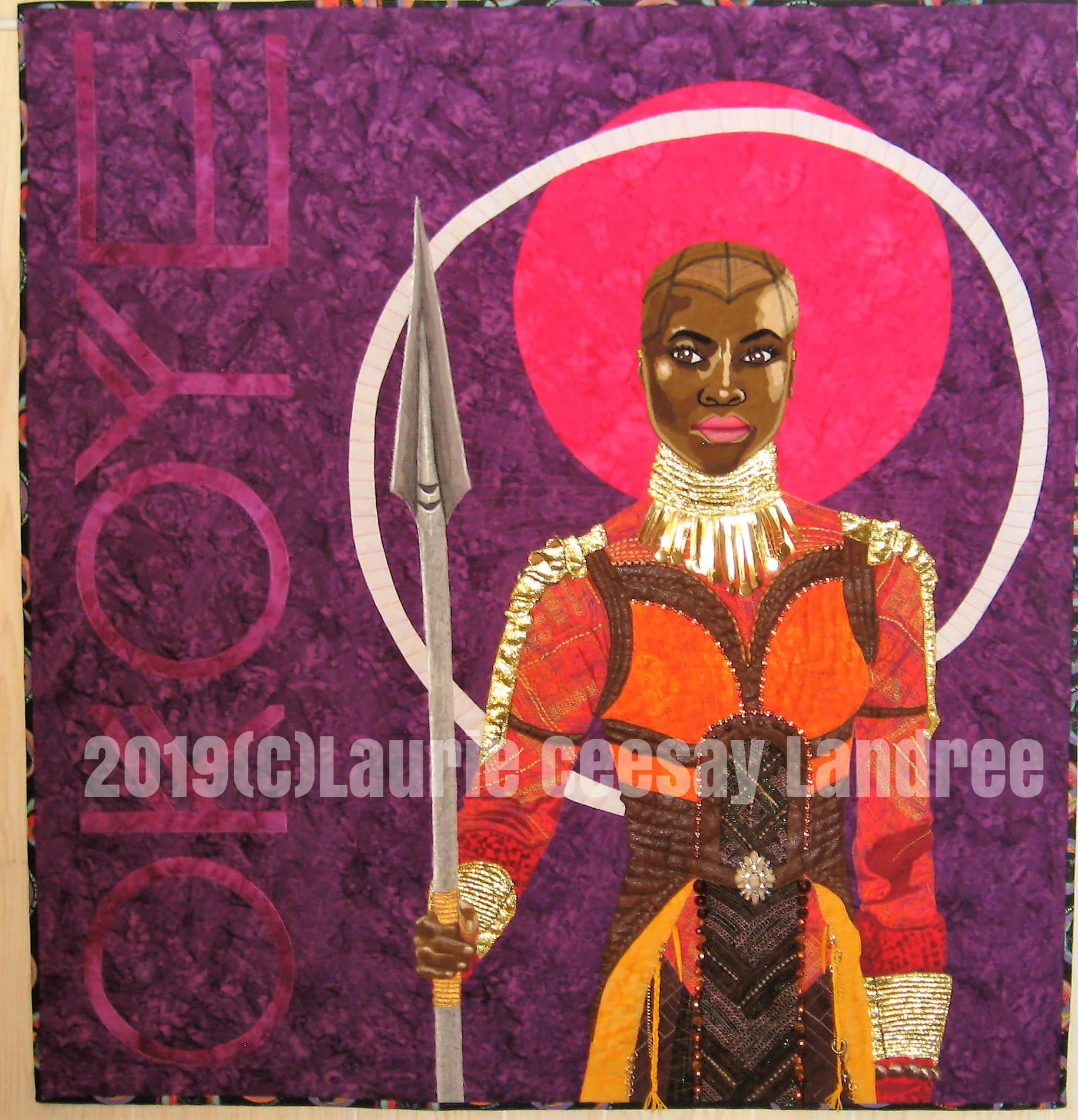 This quilt is called Okoye: Wakanda Warrior and I made it for the2019 International Quilt Festival’s quilt contest called Quilted Comics & Sci Fi. Comic books, Comic Con, Star Wars, Star Trek and Games of Thrones are many of the possible options. When I watched the 2018 movie Black Panther I was in love with the female actresses and the powerful roles they played, their fantastic costumes and that bald head and beautiful face of Okoye the General of the Dora Milaje who project the Black Panther. I loved how women ran the military army and could still be beautiful! I also loved that Okoye carried a spear! When I learned of this quilt contest I knew this was the subject matter. Black Panther began as a comic book so I felt I was safe choosing her. I researched images from Pinterest and found an image I liked. I did not cheat and print the design from the internet. I drew the design beginning on Sunday January 27, 2019 at a quilt retreat and realized the costume was very complicated. It was difficult to draw but it was so awesome I needed to continue and not wimp out on the detail.