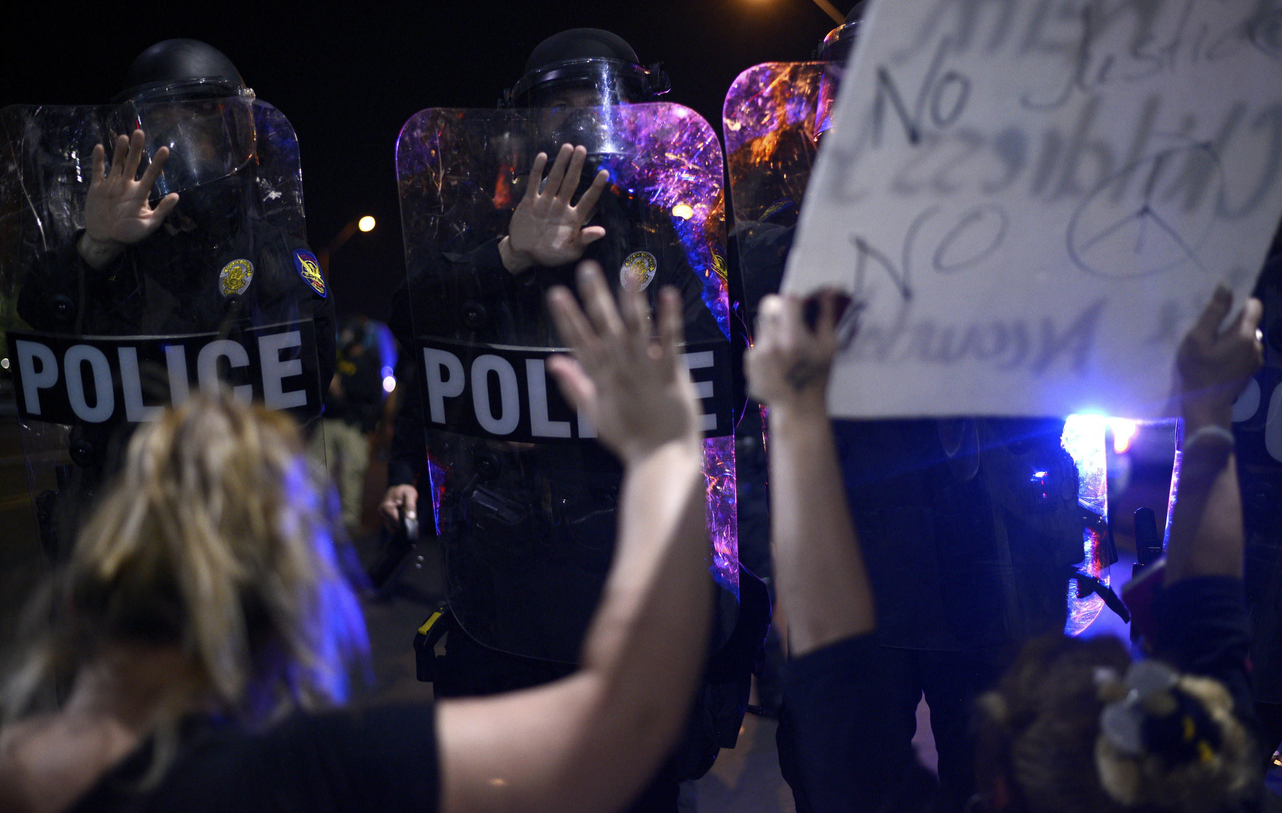  Protesters kneel before a wall of police officers on Friday, July 8, 2016, in Phoenix, Arizona. Several hundred protestors marched on downtown streets to protest recent fatal shootings nationwide of black men by police. Activists marched down 7th St