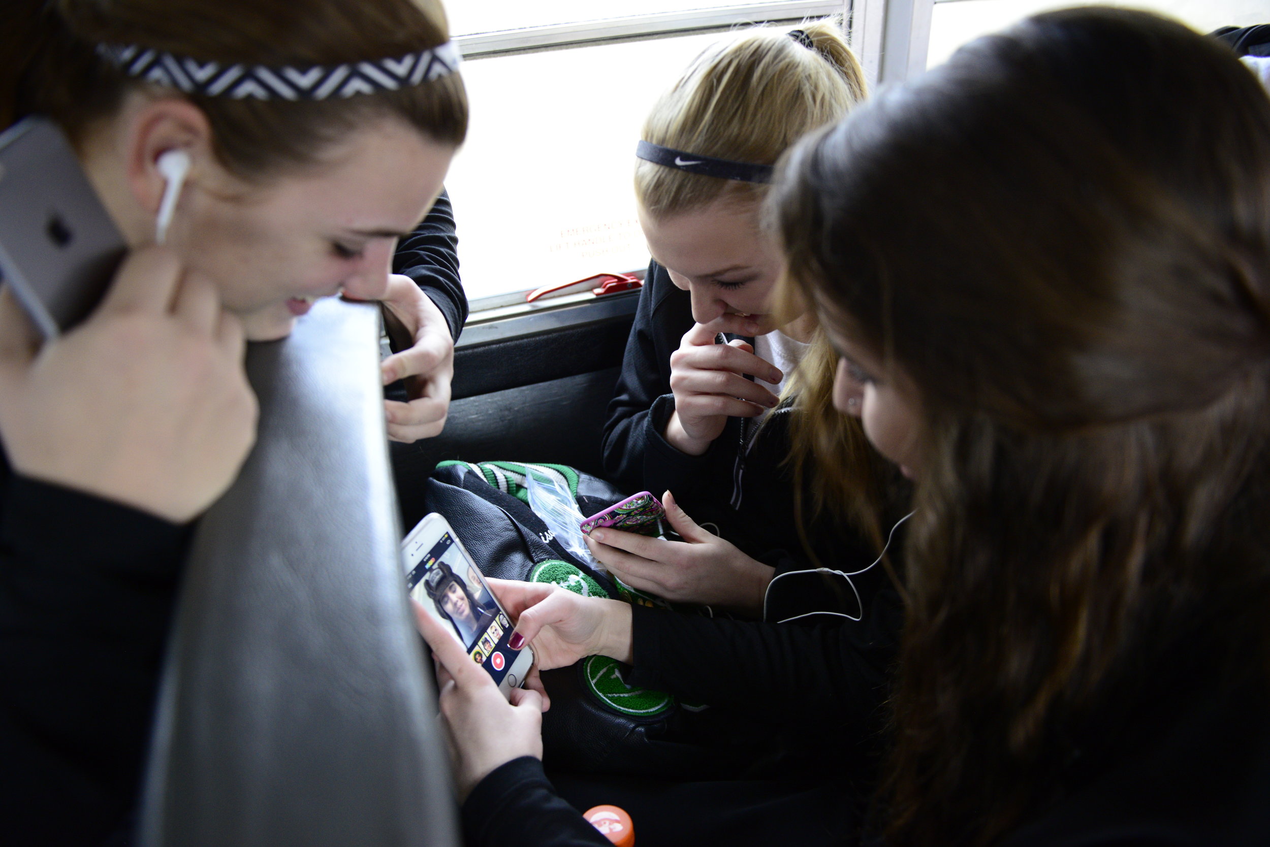  Erin Bush and Madison Ausfahl, laugh as Taylor Wilson makes funny faces in a selfie app on her iPhone Feb. 16, 2016. The trip from Kingdom City, Missouri, to Center, Missouri, took nearly an hour and half, so the players used the time to joke around