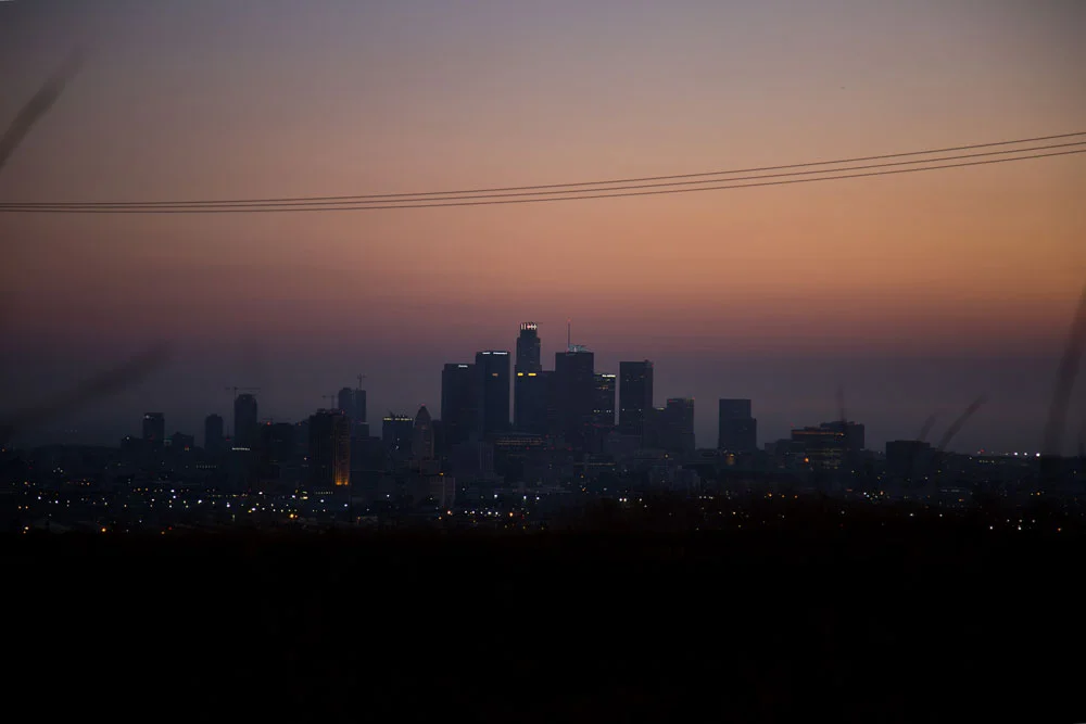 City skyline at dusk with illuminated buildings and power lines overhead. Photographed by Kayla Duffney Creative.