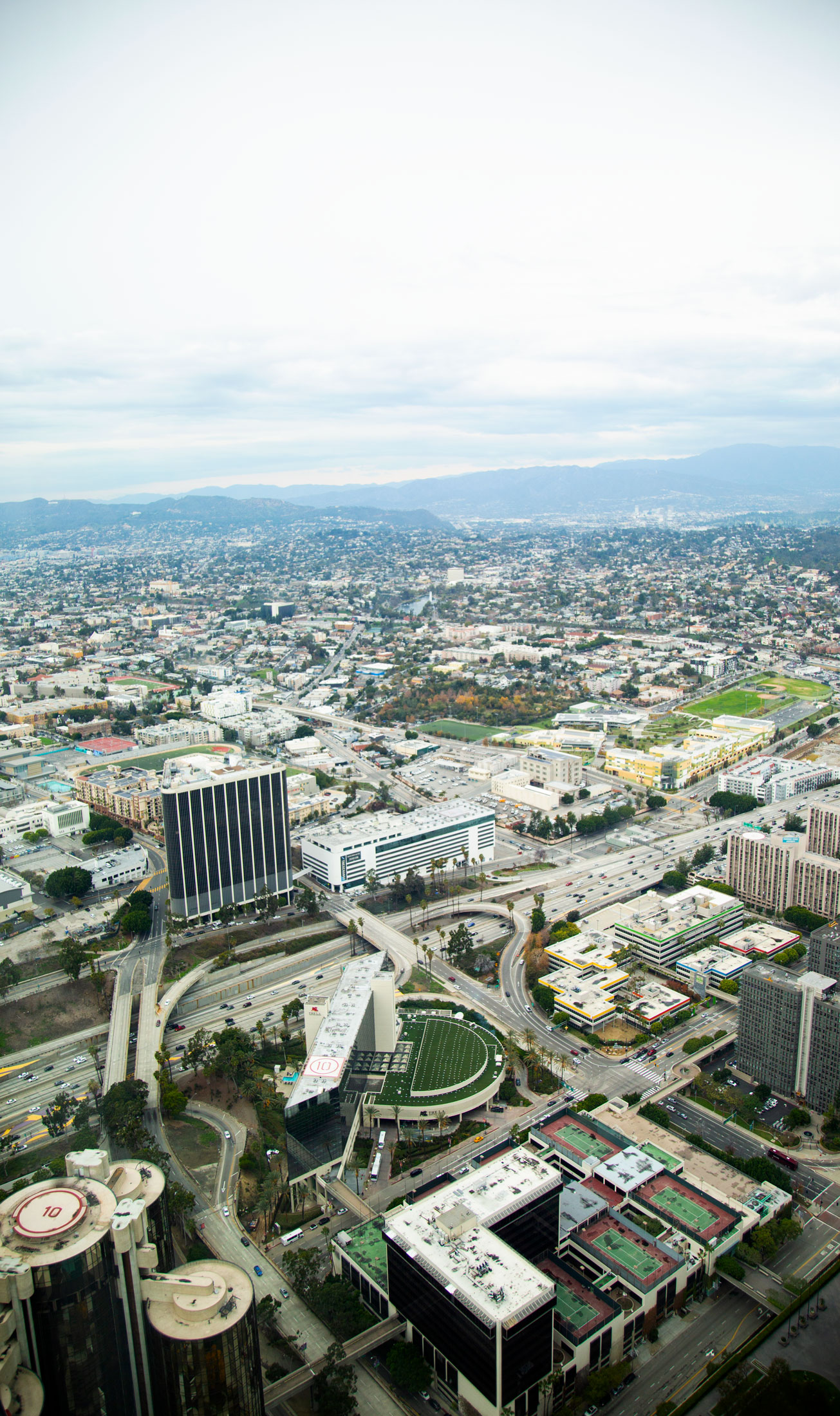 Aerial view of a cityscape with tall buildings, roads, and sports fields under cloudy sky. Photographed by Kayla Duffney Creative.