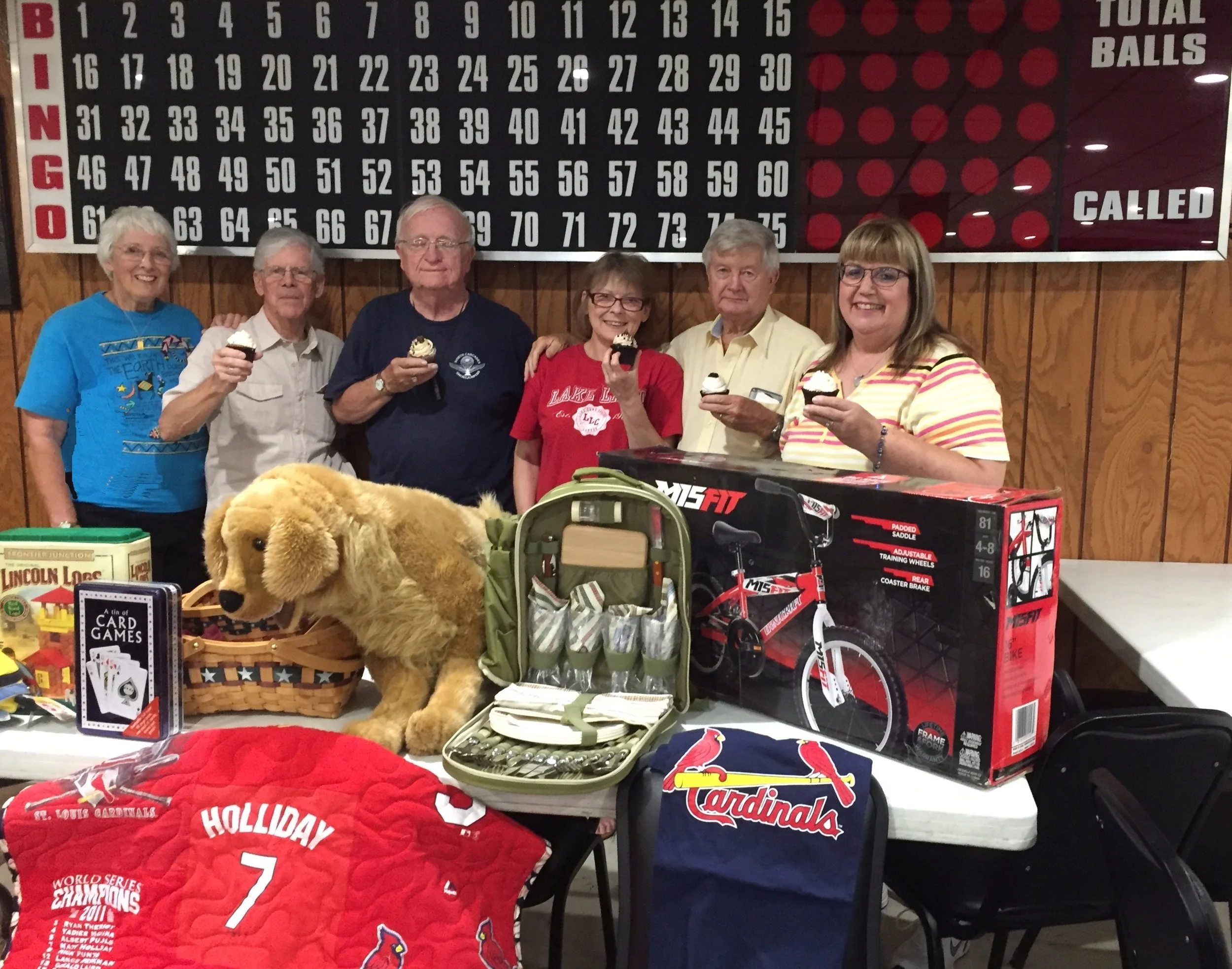 Standing behind the display of bingo prizes and raffle items, with a sweet prize be auctioned off -- cupcakes from Sweet Norma Jean’s bakery of Casey, are members of the Five Mile House Foundation board: Kathy Hummel, Tom Vance, Dick Hummel, Giuliana Dongu, Les Dallas, and Karen Jennings. 
