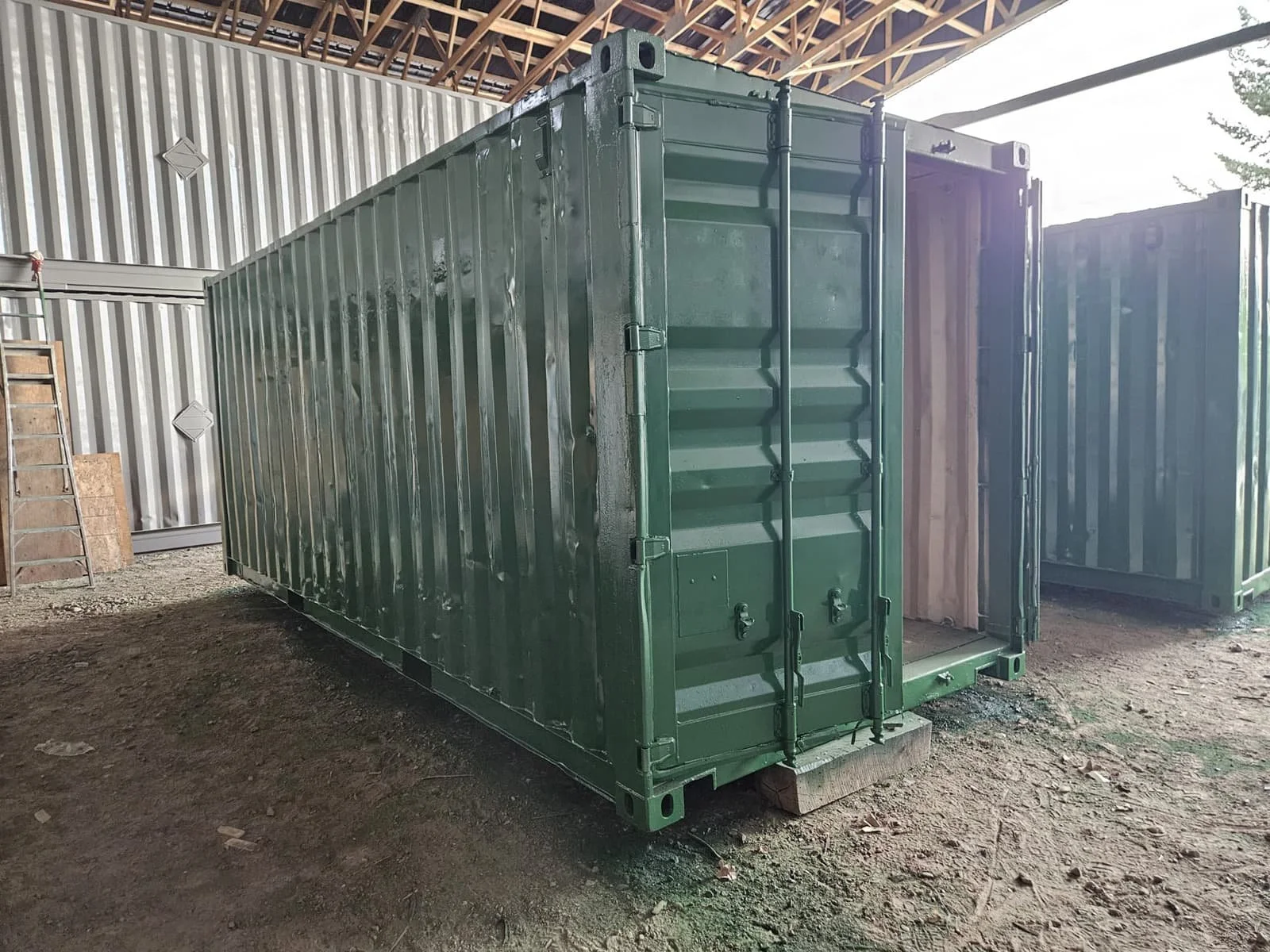 Refurbished 20ft sea can painted green with doors open, after inspection and repairs