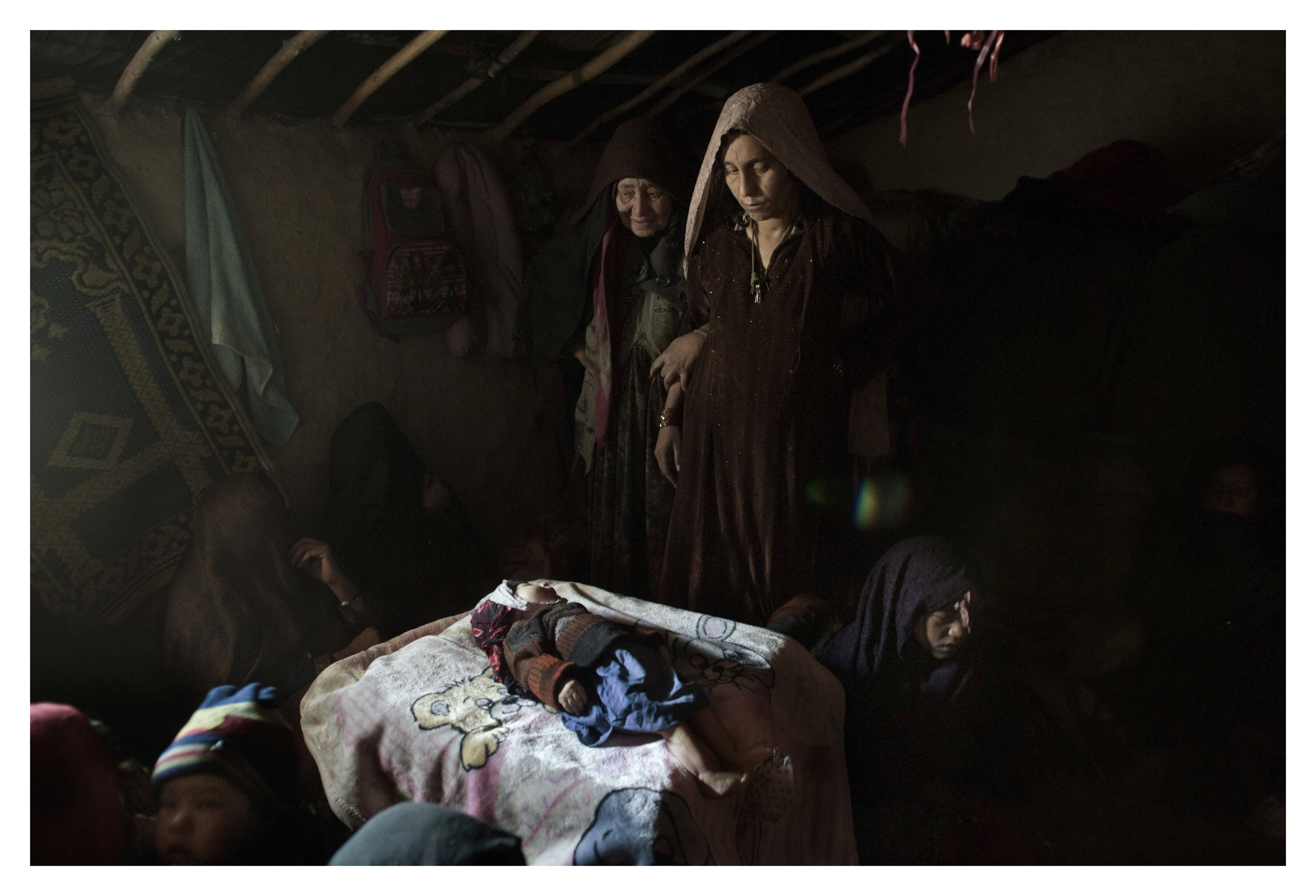  (NYT embargo until Feb. 19)
The mother of Khan Mohammad, a 3 month old child who passed away due to the cold early Wednesday morning, is comforted before the child is washed and buried in the Nasaji Bagrami Camp for displaced persons in Kabul, Afgha