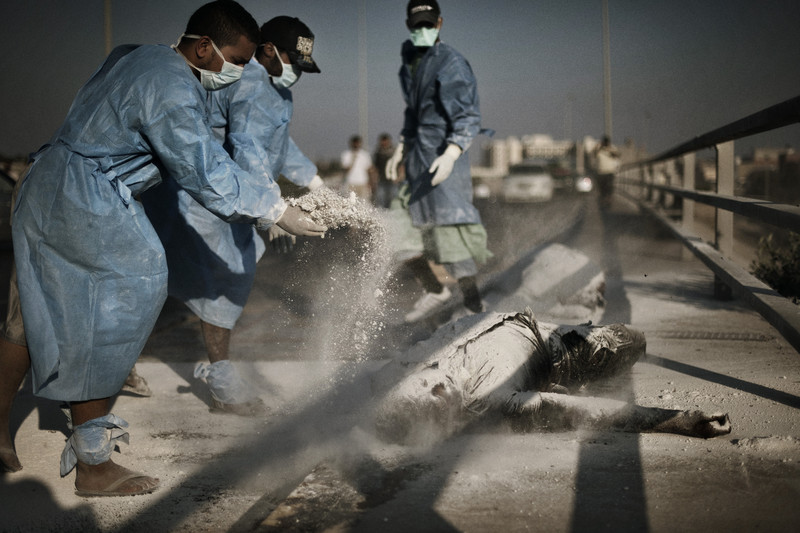  Rebel volunteers sprinkle chemical powder on a pair of corpses in the al-Intisar neighborhood of Tripoli. Volunteers have moved throughout the Libyan capital in recent days, removing corpses and garbage that were inaccessible during several days of 