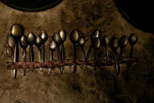 ISLAMABAD, PAKISTAN; FEBRUARY 2104
Displayed proudly on the wall, a row of mis-matched spoons found in the garbage are tacked up with a piece of ribbon in Sher Dad’s shelter. With almost no worldly possessions, Gul Dad struggles to survive along with his wife and baby son in a Pashtun-Abadi (Pashtun slum) more than five years after escaping the conflict in Bajaur.