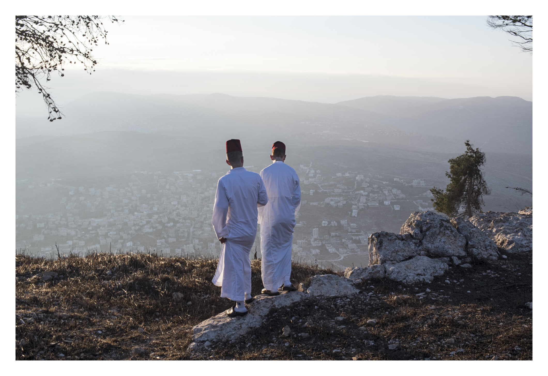  After the final prayer with book , youth of assorted ages and men take a pause on mountain and relax, overlooking the view of mountain after sunrise. Here, they are standing near the enclosed area they say is where Isaac's father was tested for sacr