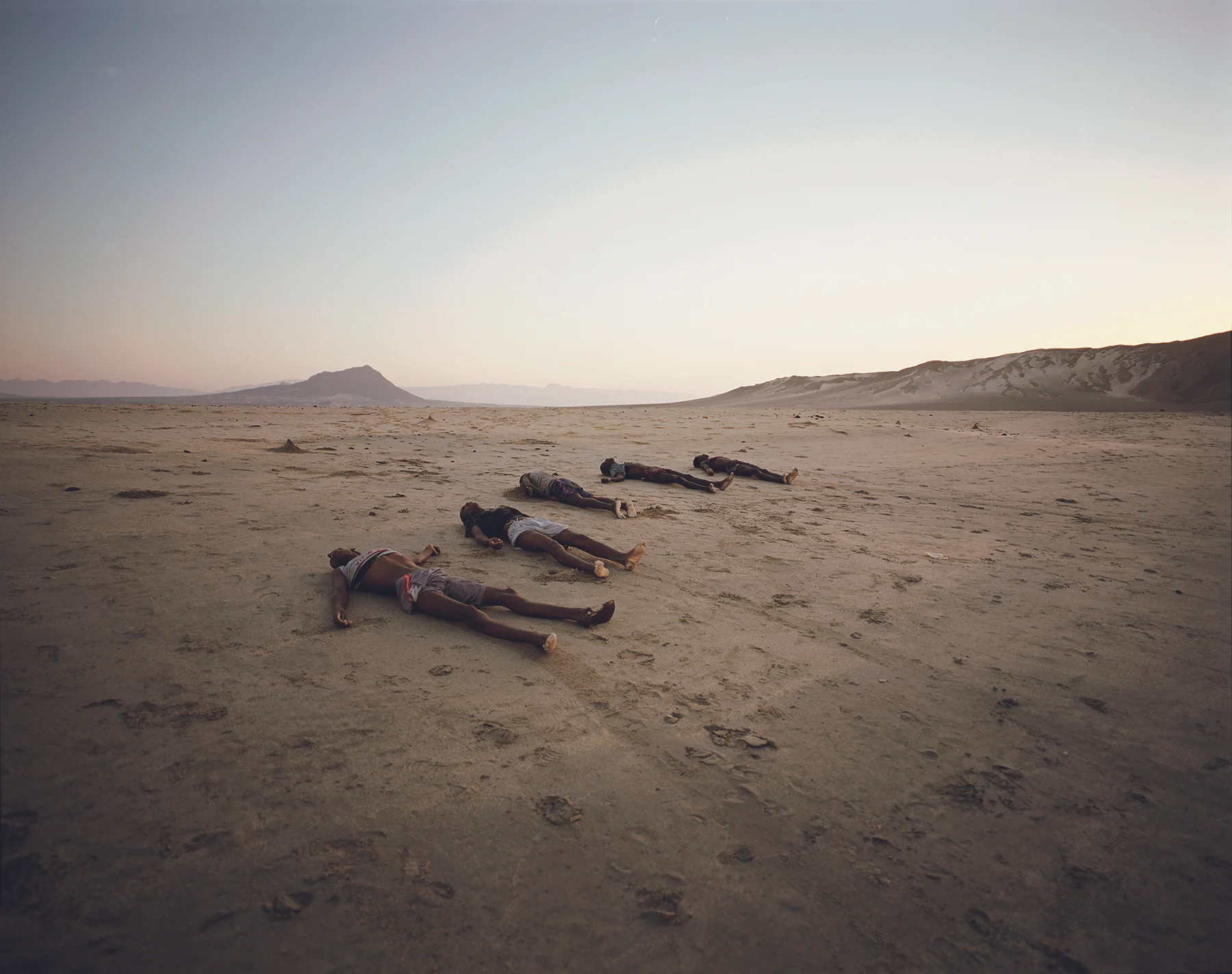Bir Ali, Yemen, May, 2007. Having been washed ashore with the morning tide, a row of corpses line Al-Baida Beach at dawn. Hauled from the water by fellow voyagers, a total of thirty-four bodies were found at sunrise as they slowly drifted inland. Just one week after an almost identical tragedy saw thirty dead on a nearby beach, Somali smugglers continue to drop their human cargo out at sea without regard for life rather than coming close to shore and risking detection. Having paid a million shillings each, for the survivors that have now finally made it to Yemen, the realisation of just what a gamble they have taken with their own destinies hits home. Most sit weeping, having spent the night looking for lost relatives, or simply in shock at the mortality that surrounds them.
