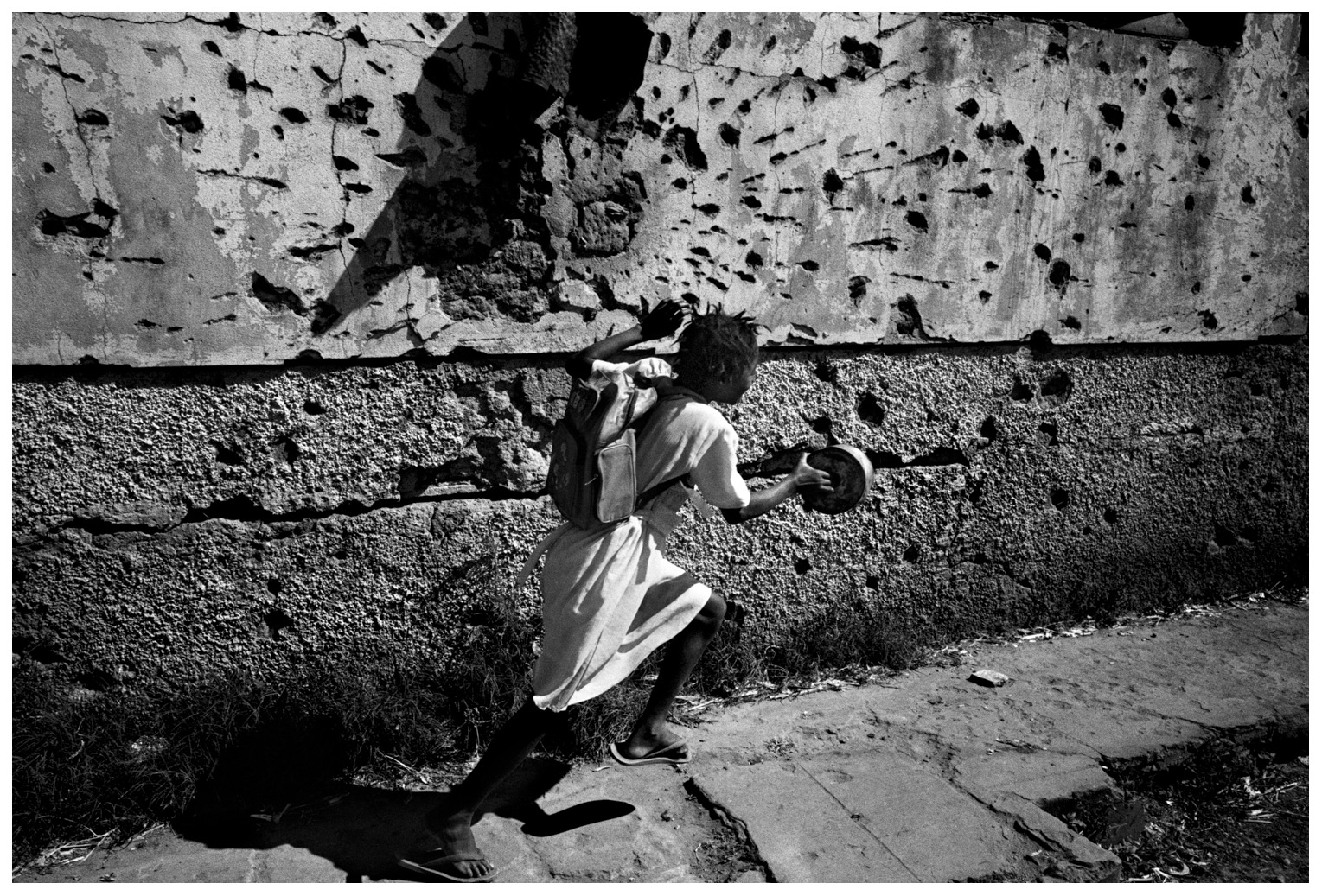  Kuito, Bie province, Angola. June, 17th 2002.
A girl running in front of a building used to be the school. 