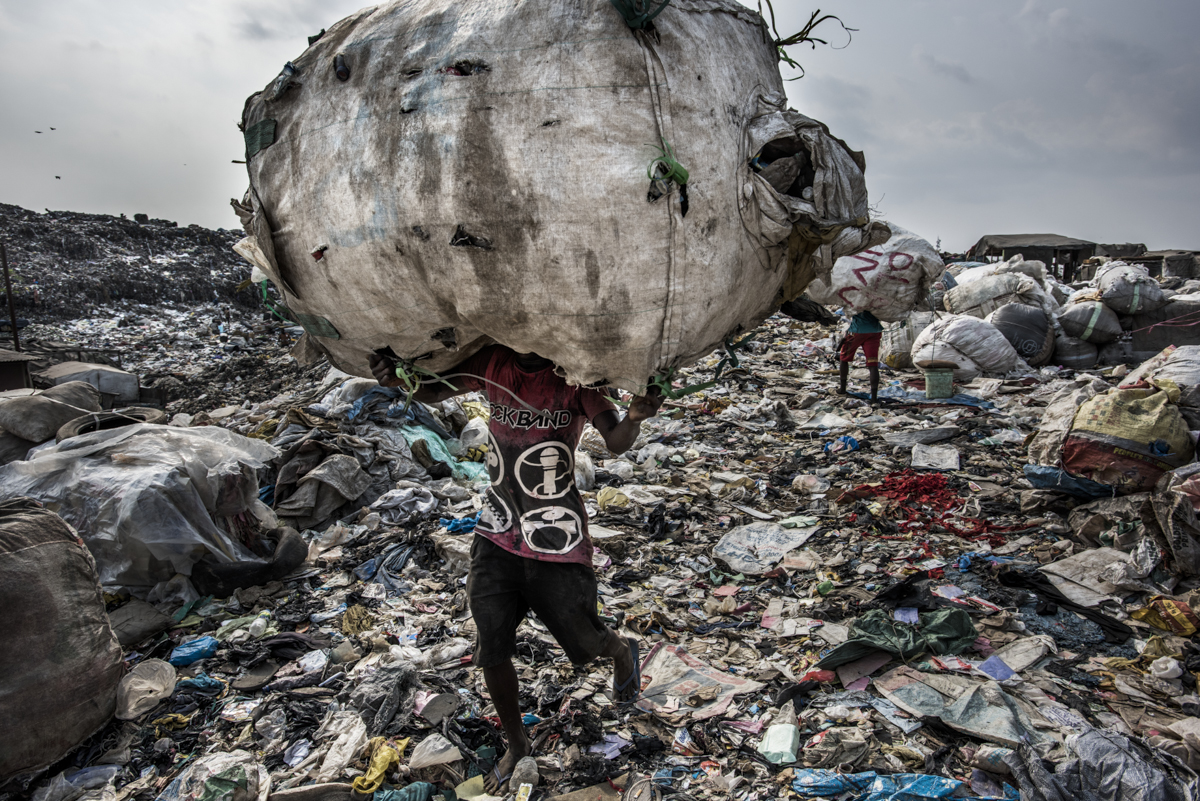  Nigeria, Lagos, 27 January 2017A man carries a huge back of pet bottles collected for recycling at the Olusosun landfill.The Olusosun landfill in Lagos receives between 3-5000 tons per day and is about 45 ha in size. About 5000 scavengers work here and often also live. They collect anything that is recyable like plastics, textiles, electronics, paper etc. The problem is that the landfill is full and the city wants to close it down. The question is where it will go, there are no incinerators and the infrastructure to formally recycle is lacking. There is one other landfill, but it needs to close as well.Remarkable is that the landfills in Lagos smell less compared to other landfills in the world: Nigerians throw away less food, because they either finish their plate or feed it to the animals.Kadir van Lohuizen / NOOR 
