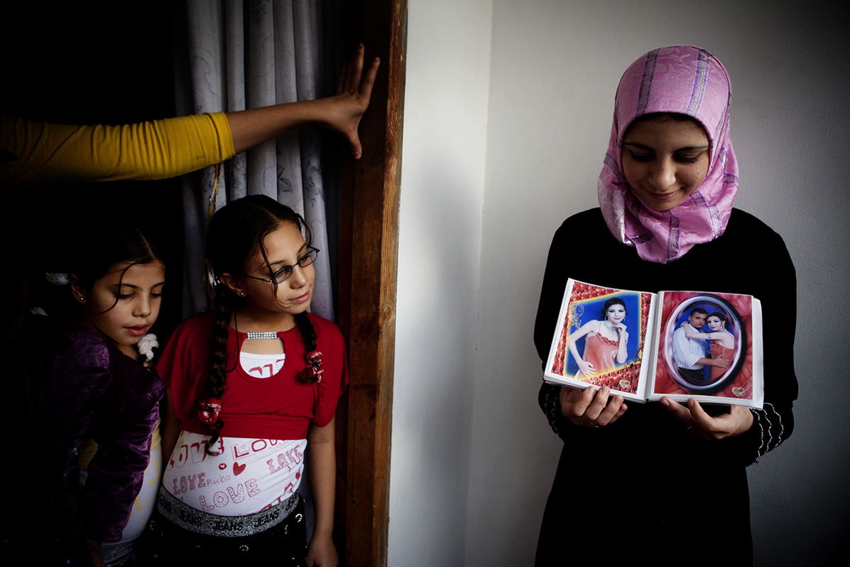 Occupied Palestinian Territories, Gaza City, October 2009, In the Gaza City home of Dr Jamal Shareef, a literature professor at Al Azhar University, his 16-year-old niece (right) shows pictures of her fiancé. 