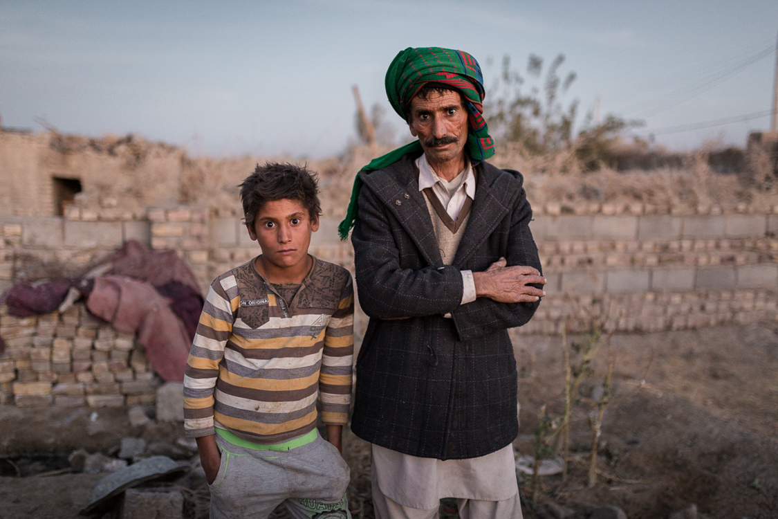  A fisherman poses for a portrait in Ali Akbar town, a small town near Zabol. He has almost quit fishing as there is no water in the lake anymore. His grandson (left) might not have the option to be fisherman, yet there are no many other options for 