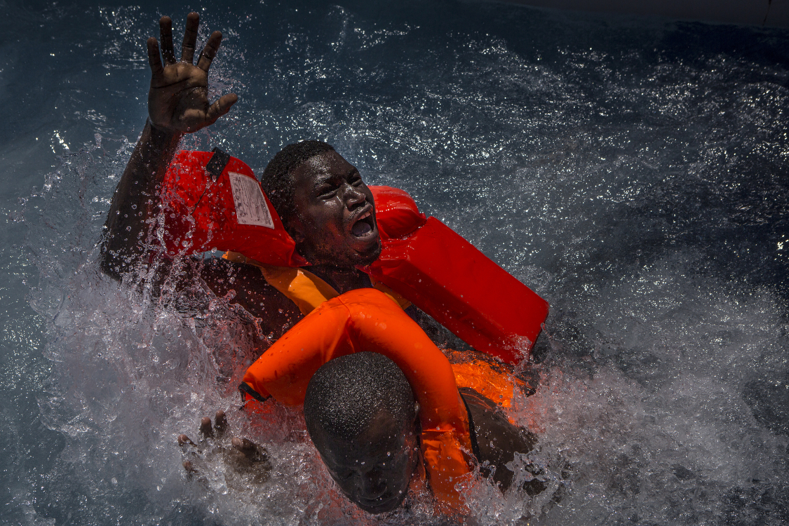  Two men panic and struggle in the water during their rescue. Their rubber boat was in distress and deflating quickly on one side, tipping many migrants in the water. They were quickly reached by rescue swimmers and brought to safety.  � Mathieu Will
