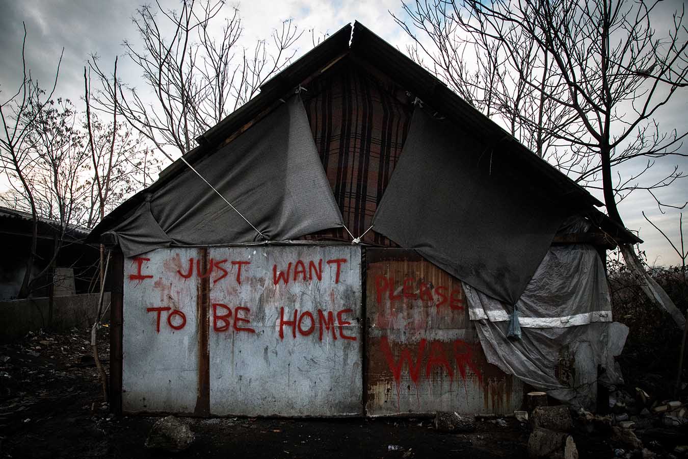  A metail shack with graffiti reading "I just want to be home.", inside the abandoned industrial complex turned into makeshift refugee camp, in the area of Belgrade's Central Station.  