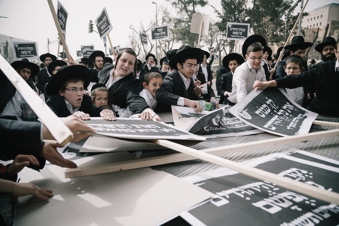  Young Ultra-Orthodox Haredim try to catch demonstration signs on a protest in Jerusalem on 2th March, 2017, at a bill that would cut their community's military exemptions and end a tradition upheld since Israel's foundation. Ultra-Orthodox leaders h