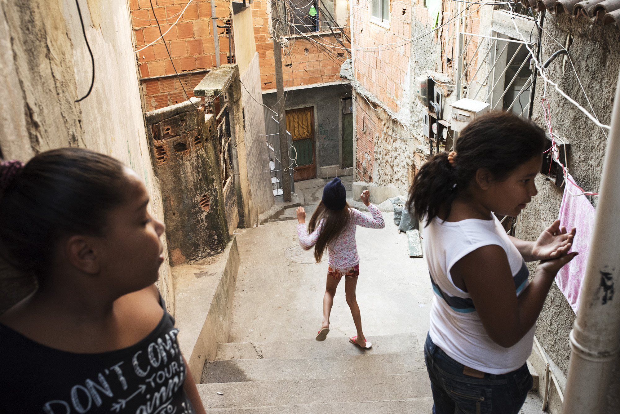  Inside the favela Vila Cruzeiro a bunch of girls are playing outside in the narrow alley in front of their houses.  