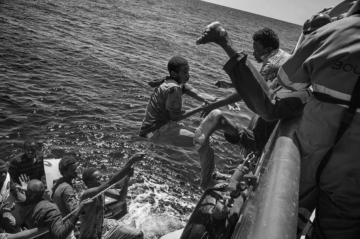  Migrants on board of a sinking rubber dinghy carrying 95 people climb on board a rigid-hulled inflatable boat (or RIB) launched by the MSF the Bourbon Argos search and rescue ship patrolling the SAR zone of the Mediterranean Sea. 21 August 2015. 