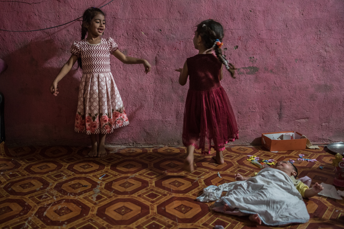  Fatma and Tiktum dance at home on a birthday while their newborn brother, Abdallah, is laying on the floor.
Iraq, 04/10/2018 