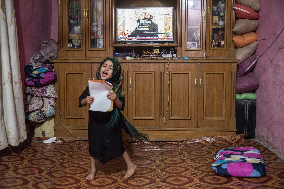  Tiktum, 6, dances and chants as a Shiite cleric is talking on TV. She sings a mix of names, random words, and bits of the Fatiha, the first Sura from the Qur�an that she is currently learning at school. 
Iraq, 04/10/2018 