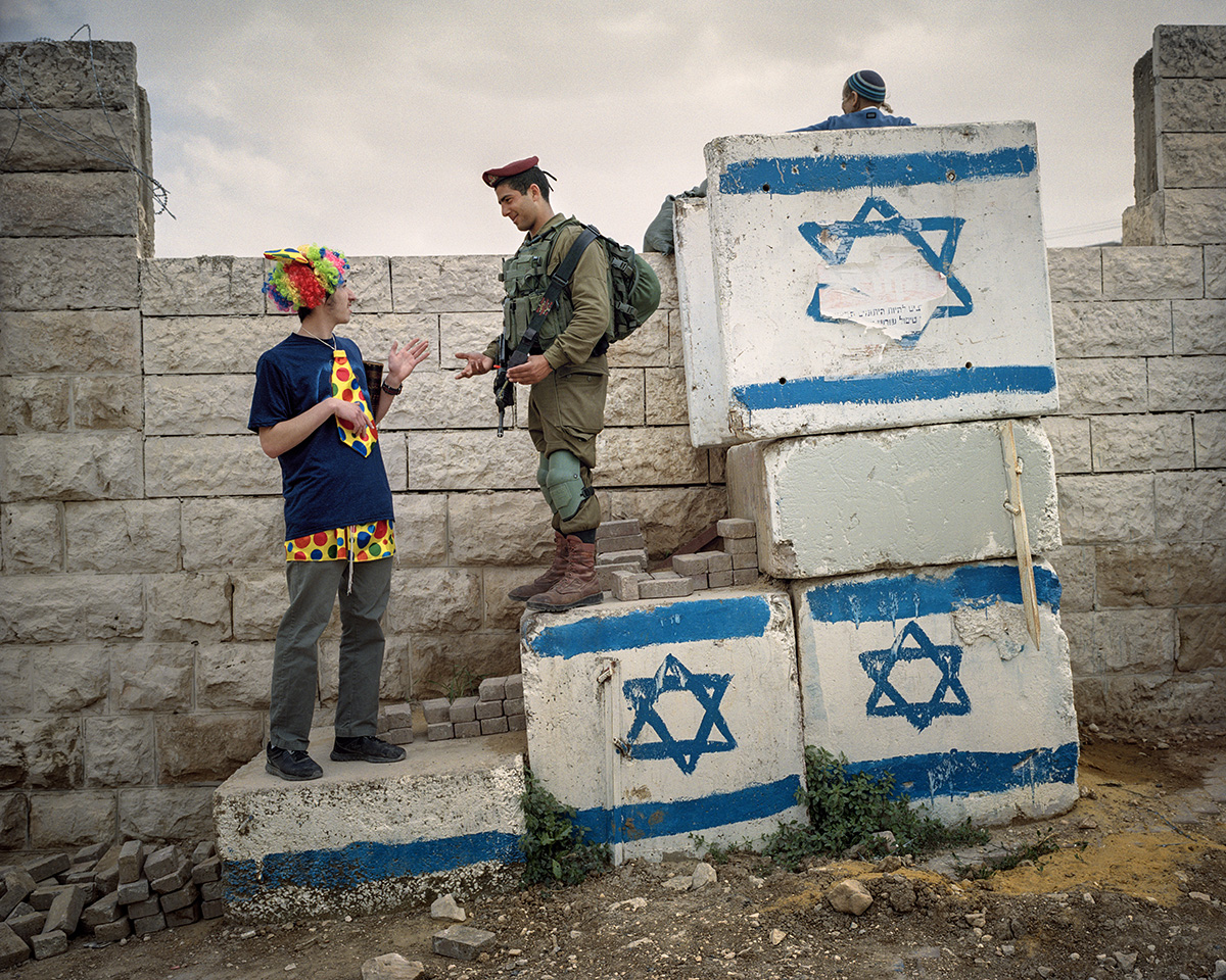  12. Maerz 2017. Hebron, Westjordanland. Ein israelischer Soldat scherzt mit einem Siedler herum, der sich fuer das Purimfest verkleidet hat. Purim ist ein froehliches Fest, die Menschen kostuemieren sich, und der Alkohol fliesst. Gefeiert wird die R