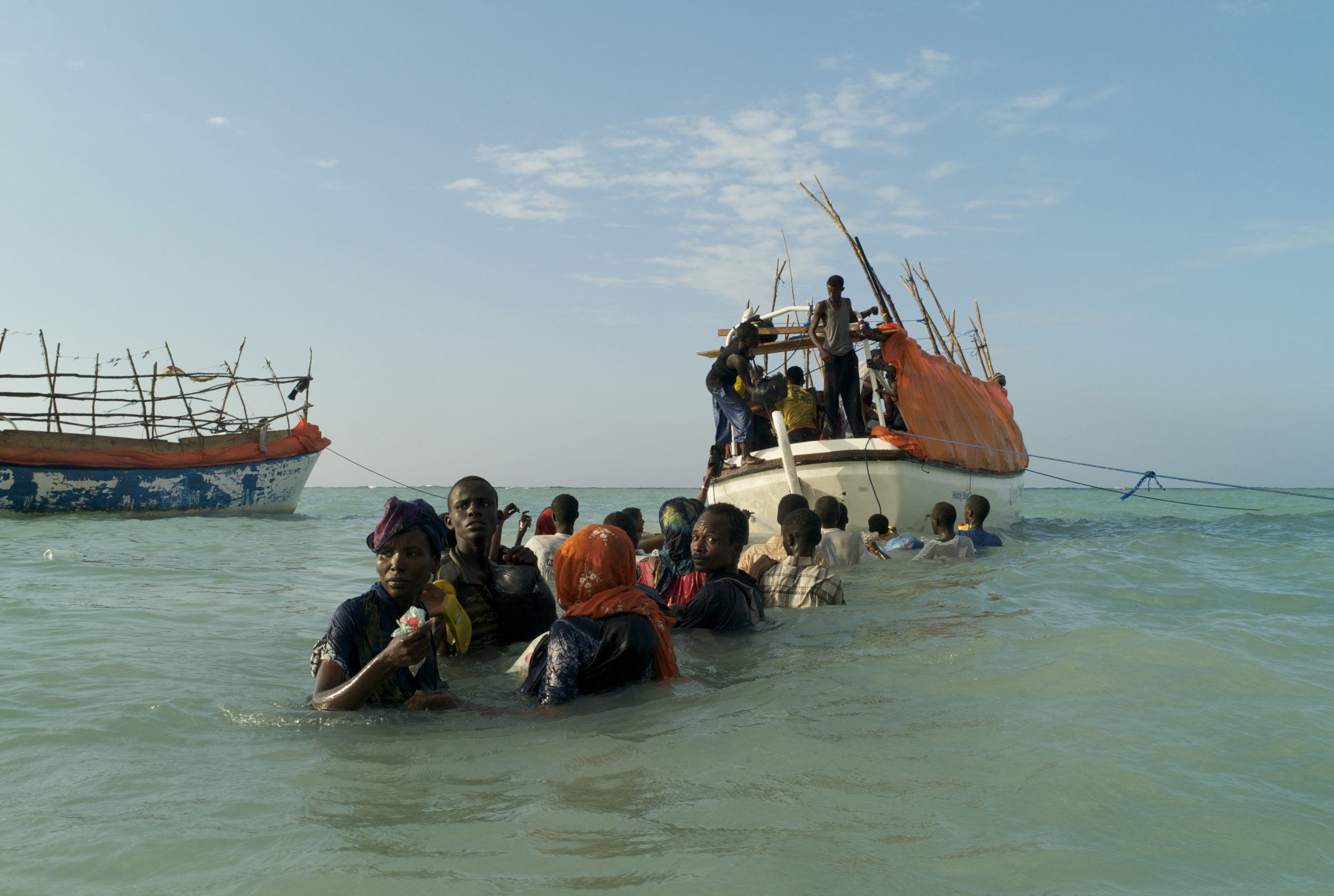  Standing in choppy shoulder deep water, Somali refugees look back anxiously from the sea as they try to locate friends and relatives left behind on Shimbiro Beach. Preparing to board one of three smuggler’s boats that will depart simultaneously for 