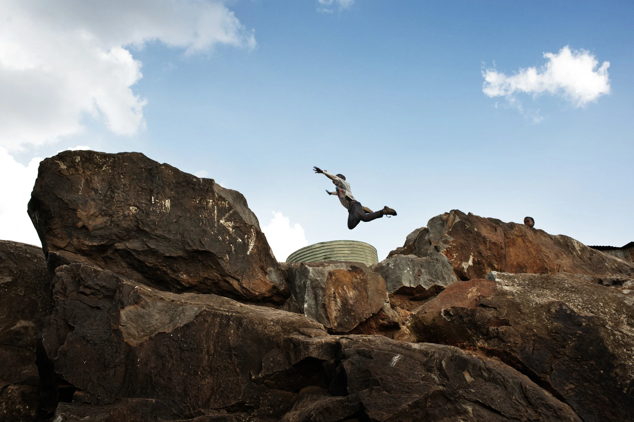  Kibera, Kenya. 2 July 2011

A boy leaps from a rock into a tank filled with water. Despite extreme poverty, endemic crime and widespread disease, Kibera is buzzing with life and children can be seen cheerfully playing in the alleyways around.
 