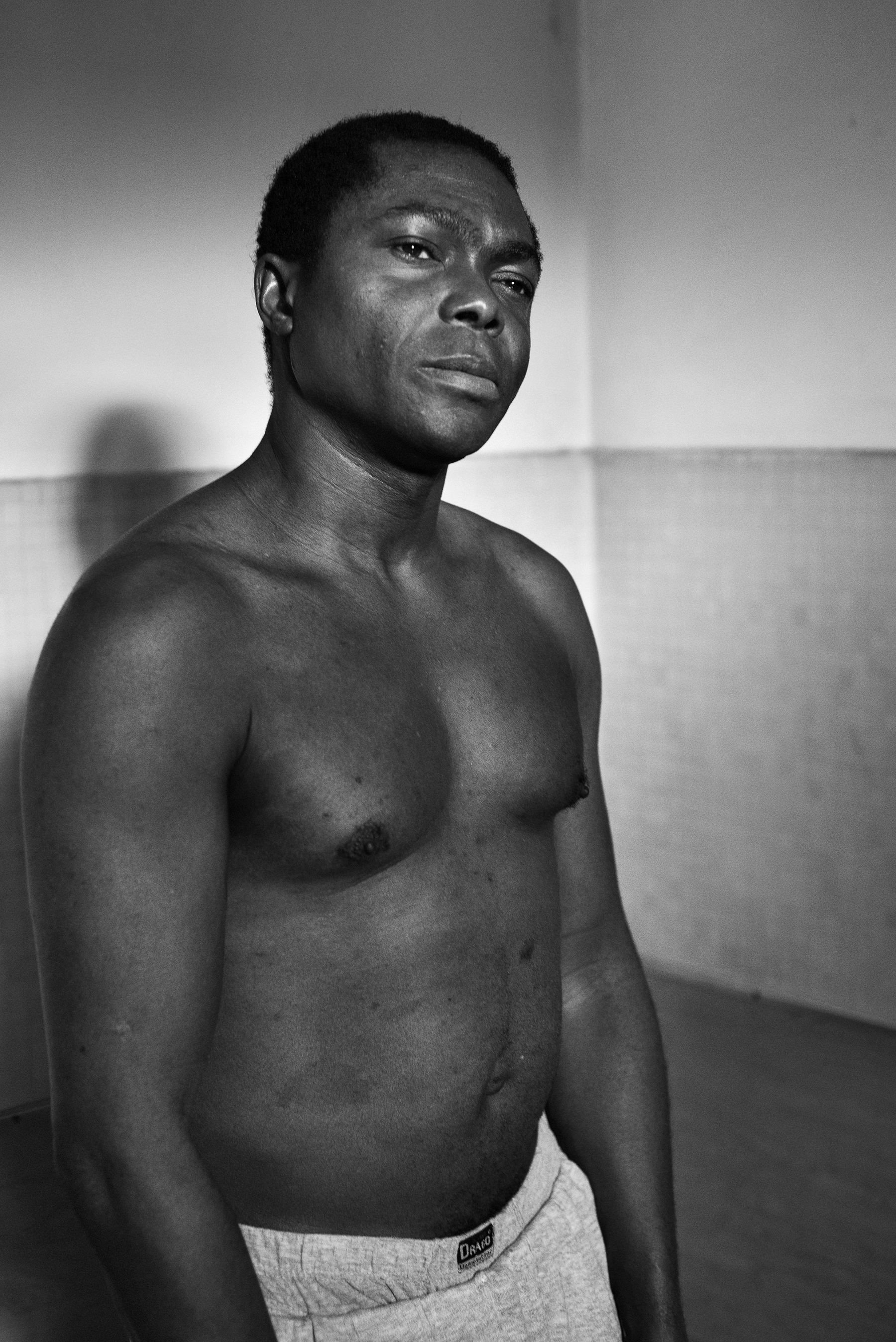  Rok Ibe (30) in the showers� entrance inside the Public Baths of Via Bianz� in Turin, Italy; December 2018.
Mr. Ibe lives with his parents on the outskirt of Torino; given that they can�t afford to pay housing bills, they are forced to live without 