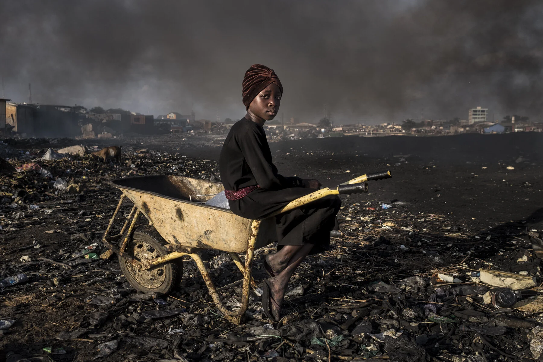  Ghana, Accra, November 2018. Rashida is a young girl originally from the North of Ghana, she sells water in the scrap yard of Agbogbloshie. Along with other girls living in the area, she carries water bags into a wheelbarrow and sell them for 1 Ghan
