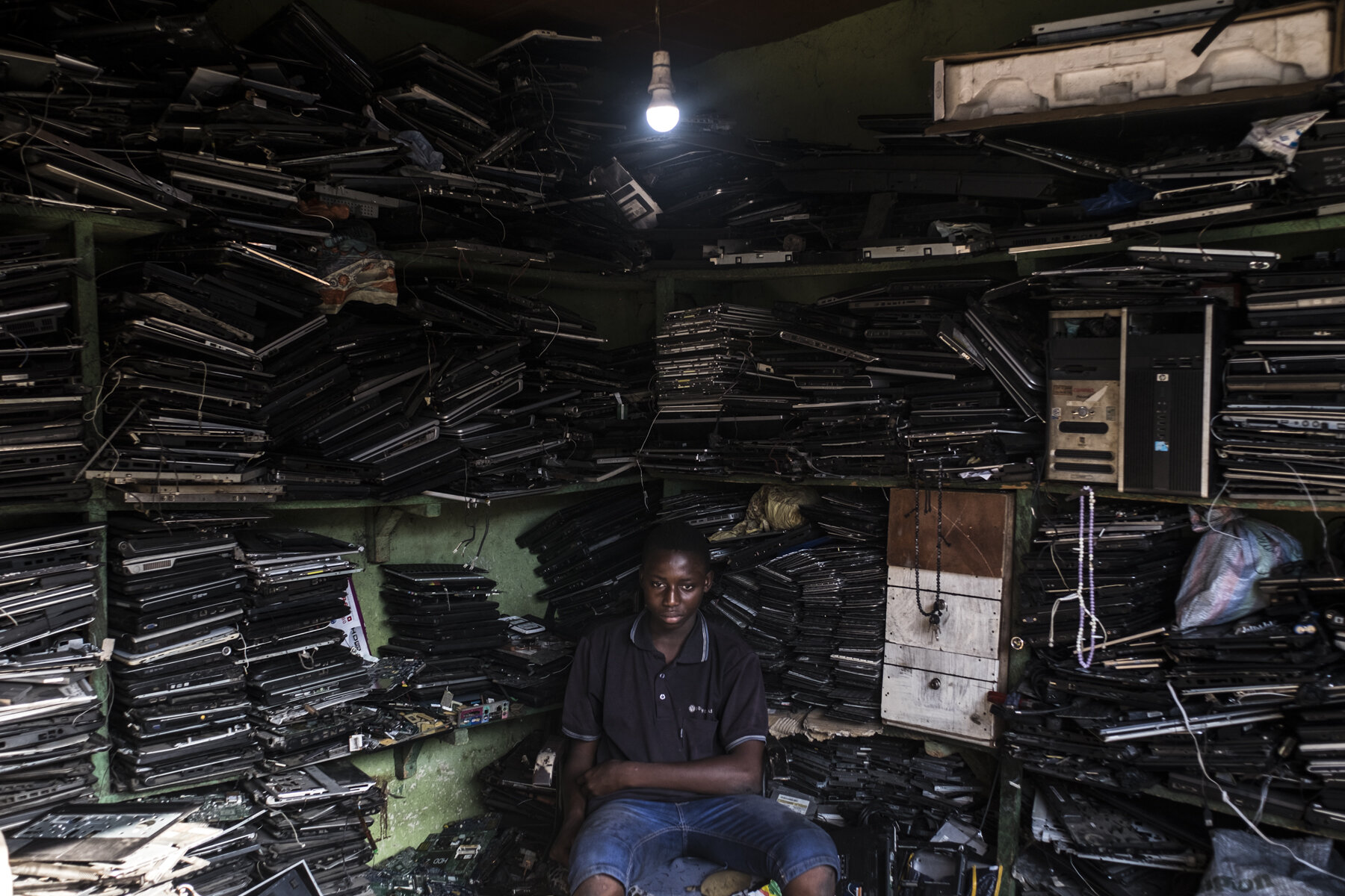  Ghana, Accra, October 2018. Zakiri, 18 years old, inside his brother's shop in the Sodom and Gomorrah slum. The two brothers Zakiri and Youssif live and work in the slum, recuperating no functional computers and laptops, dismantling them and re-sell