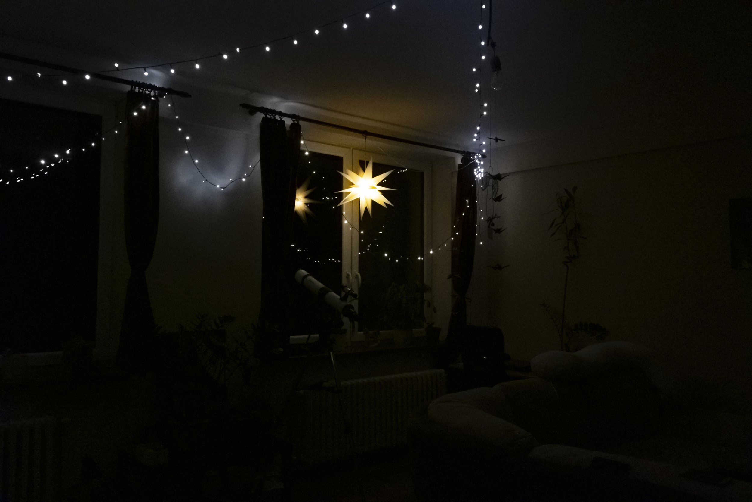  A young couple is trying to combine cost-effectiveness with cosiness in their apartment, so they are using only LED string lights and a starlight that can charmingly and efficiently illuminate the space. 