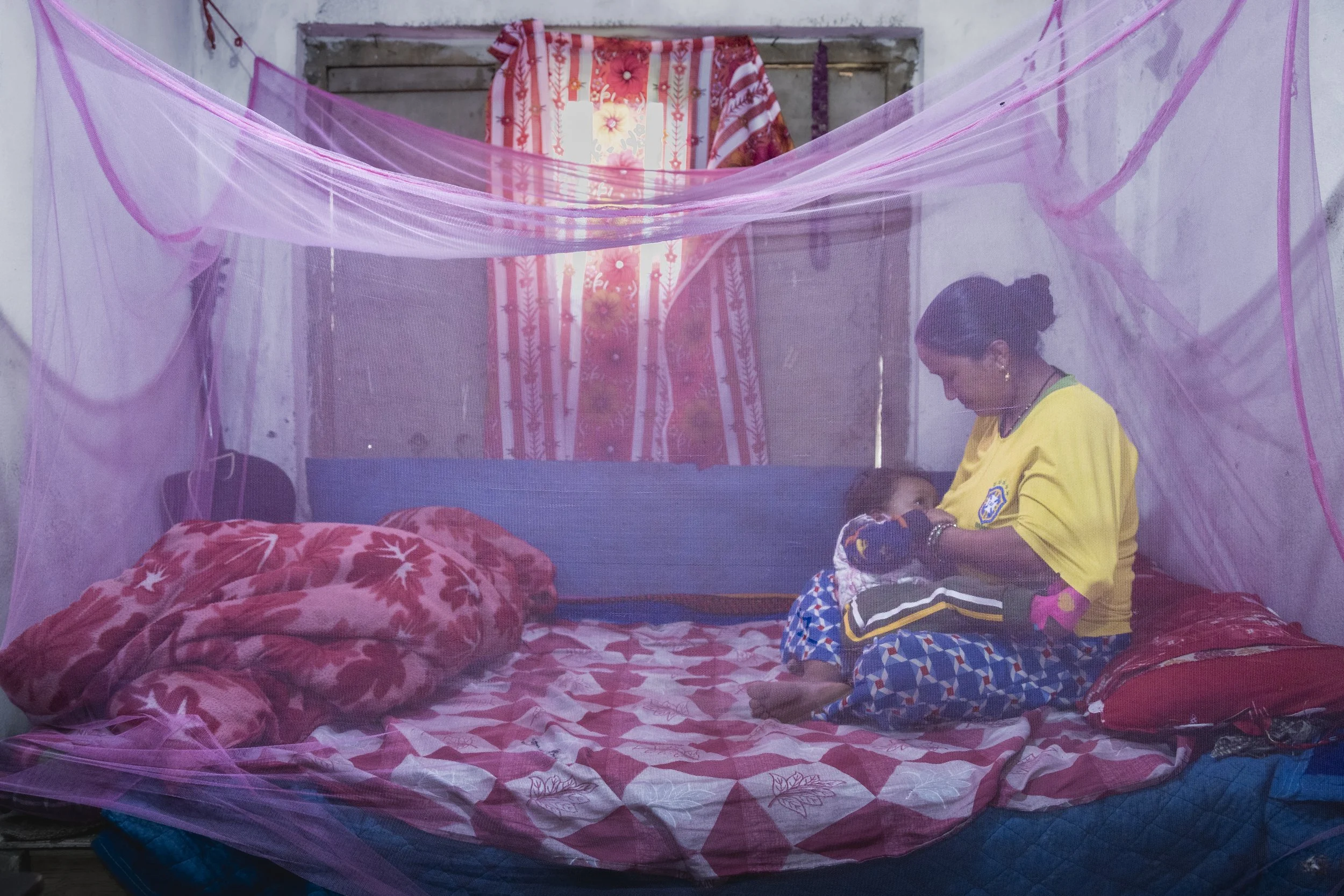 Devi Kannya Katayata breastfeeds her two-year-old son Nehan Budha under a mosquito net inside their home in Chandannath, Jumla, Nepal. Photo by Yuri Segalerba.